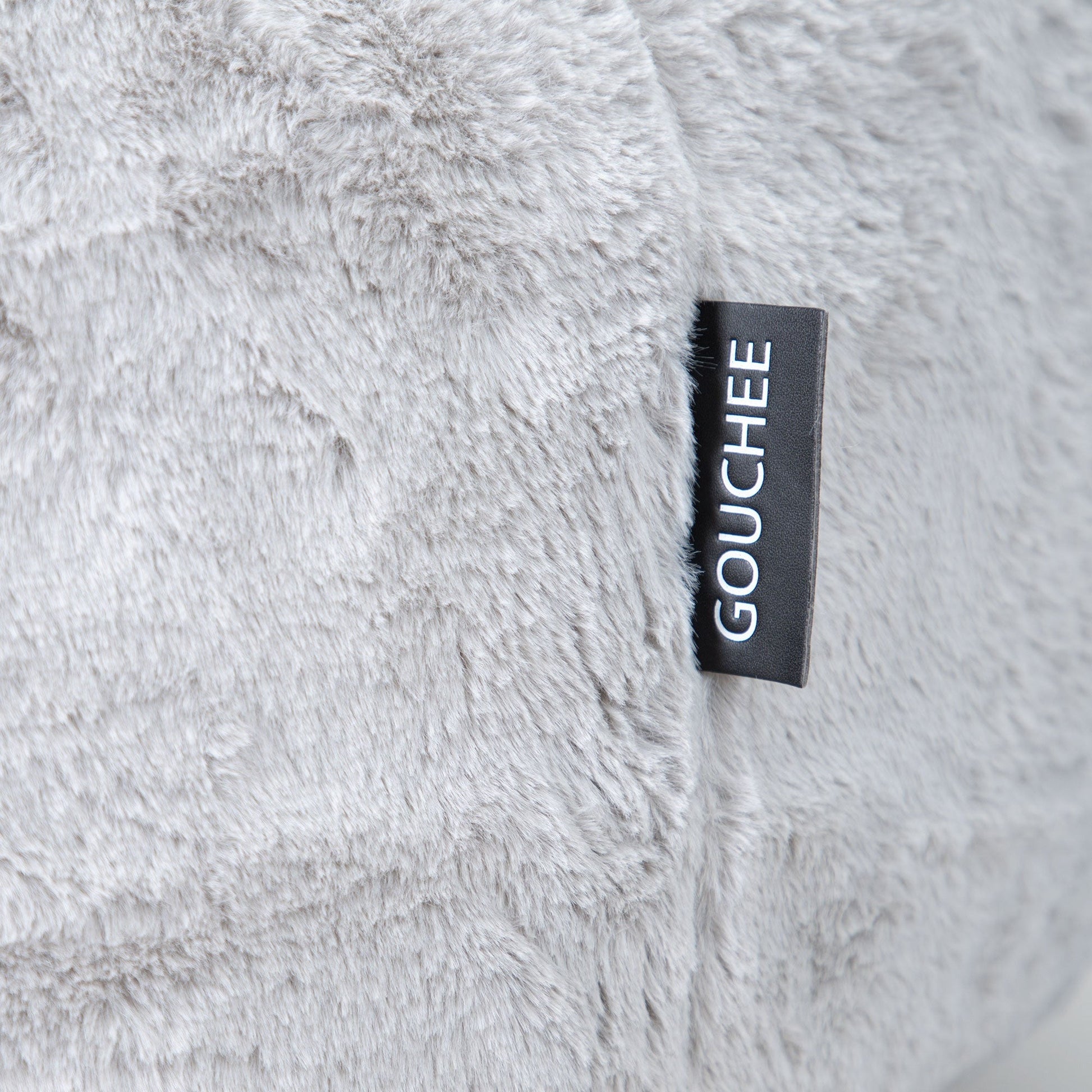 Close-up of a fluffy gray fabric with a 'Gouchee' label.