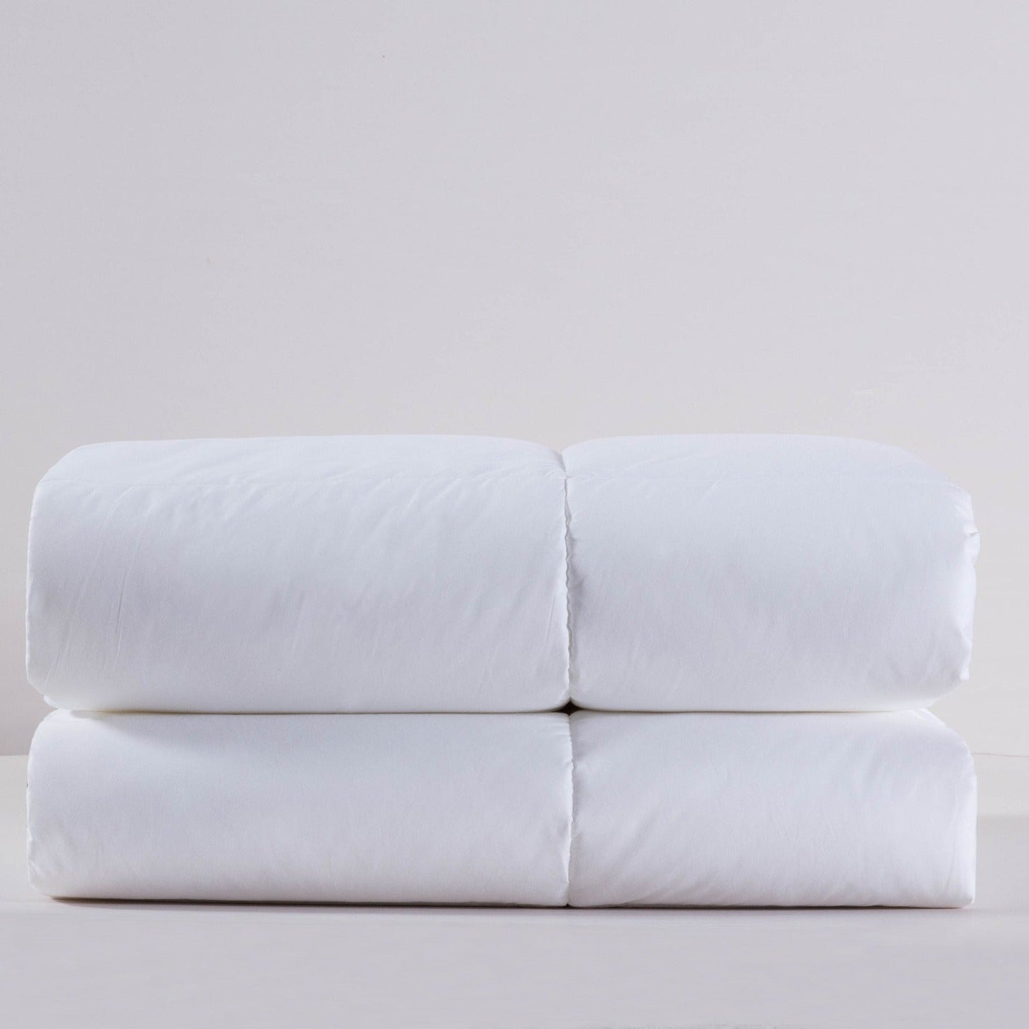Folded white bed sheets on a light gray background