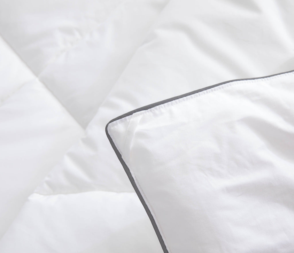 Close-up of white bedding with a dark trim on a soft fabric background