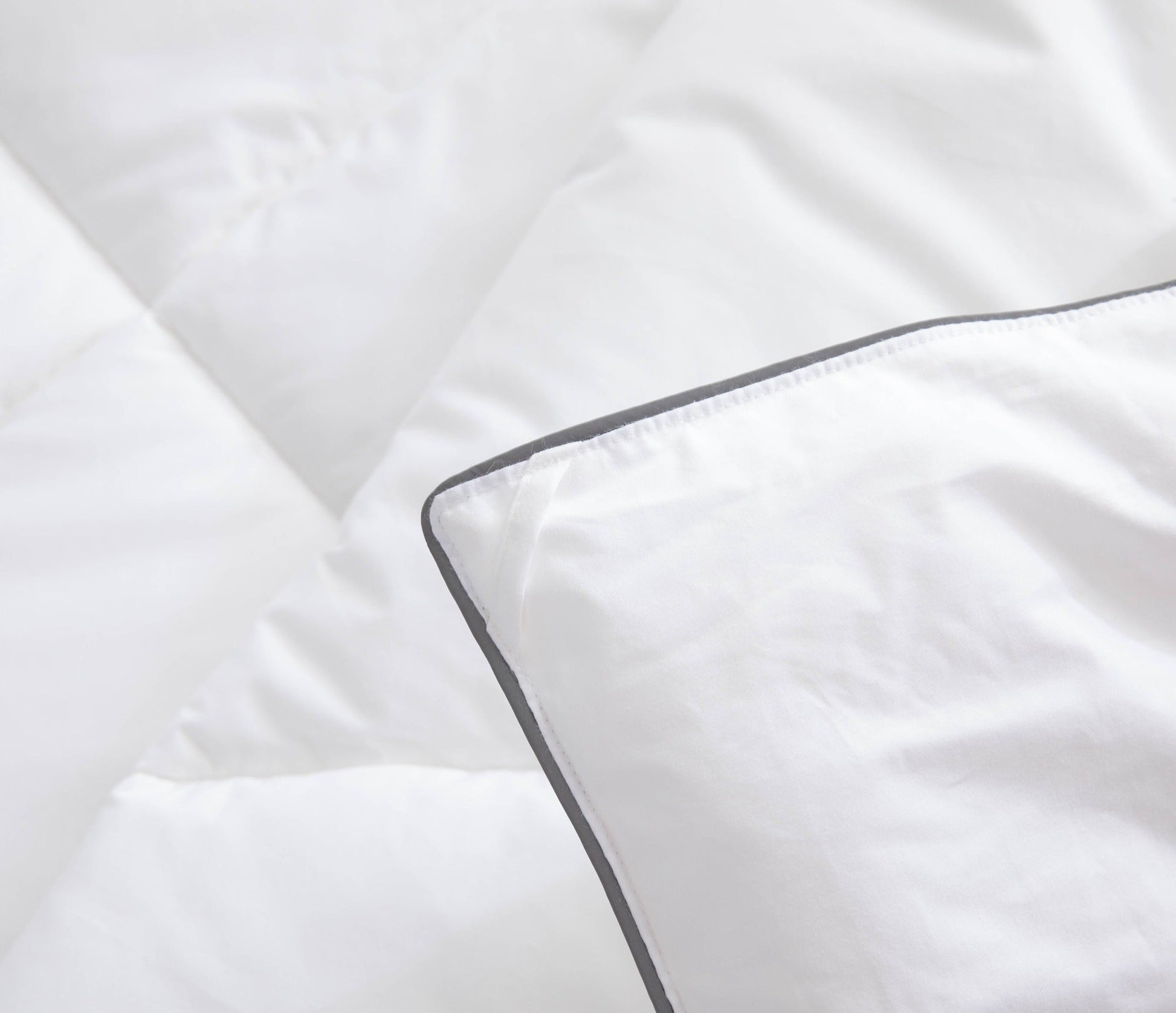 Close-up of white bedding with a dark trim on a soft fabric background
