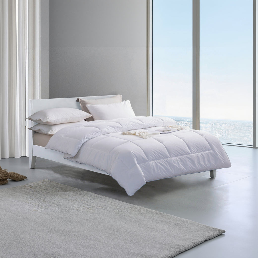 White bed with comforter and pillows in a modern bedroom setting