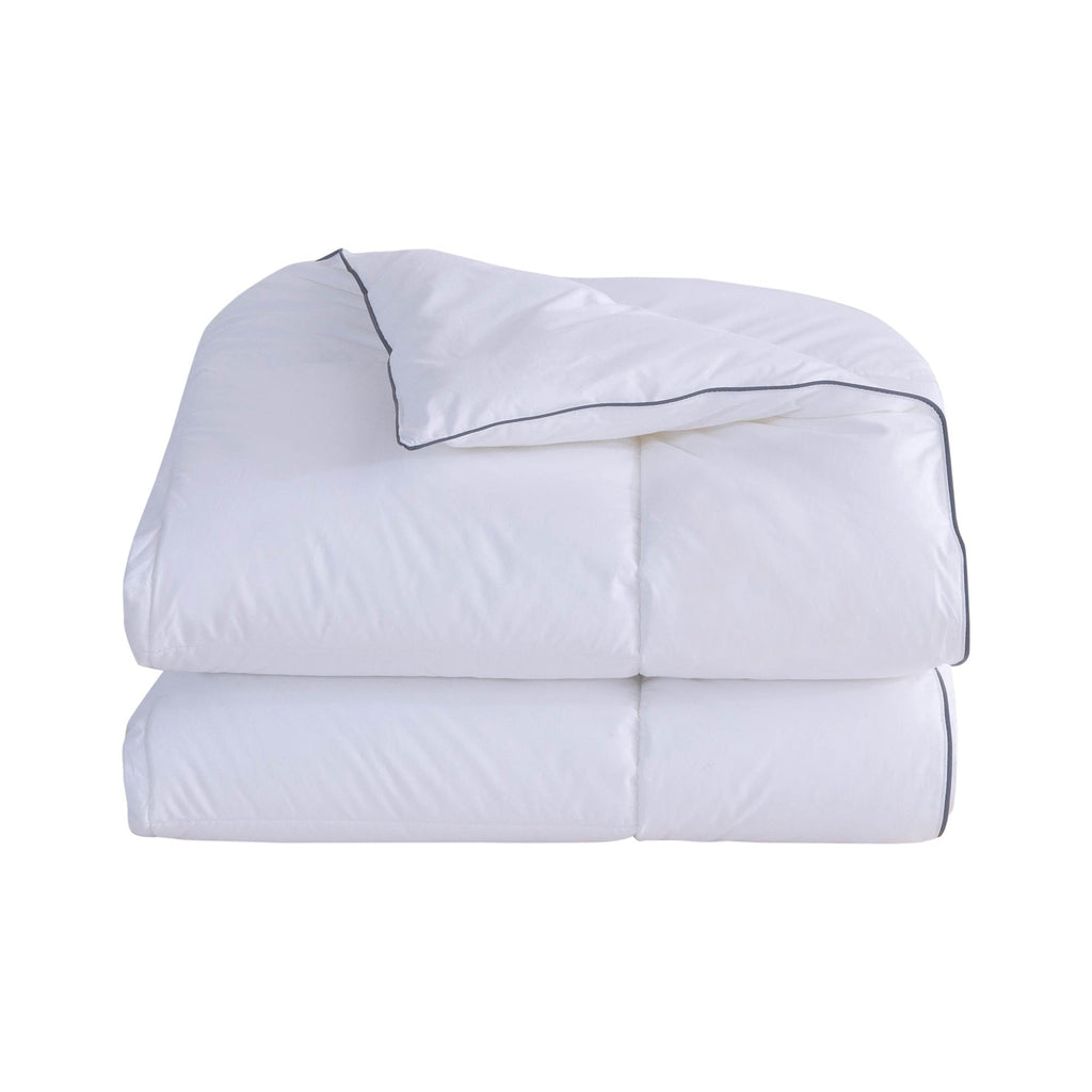 Folded white comforter with black piping on a white background