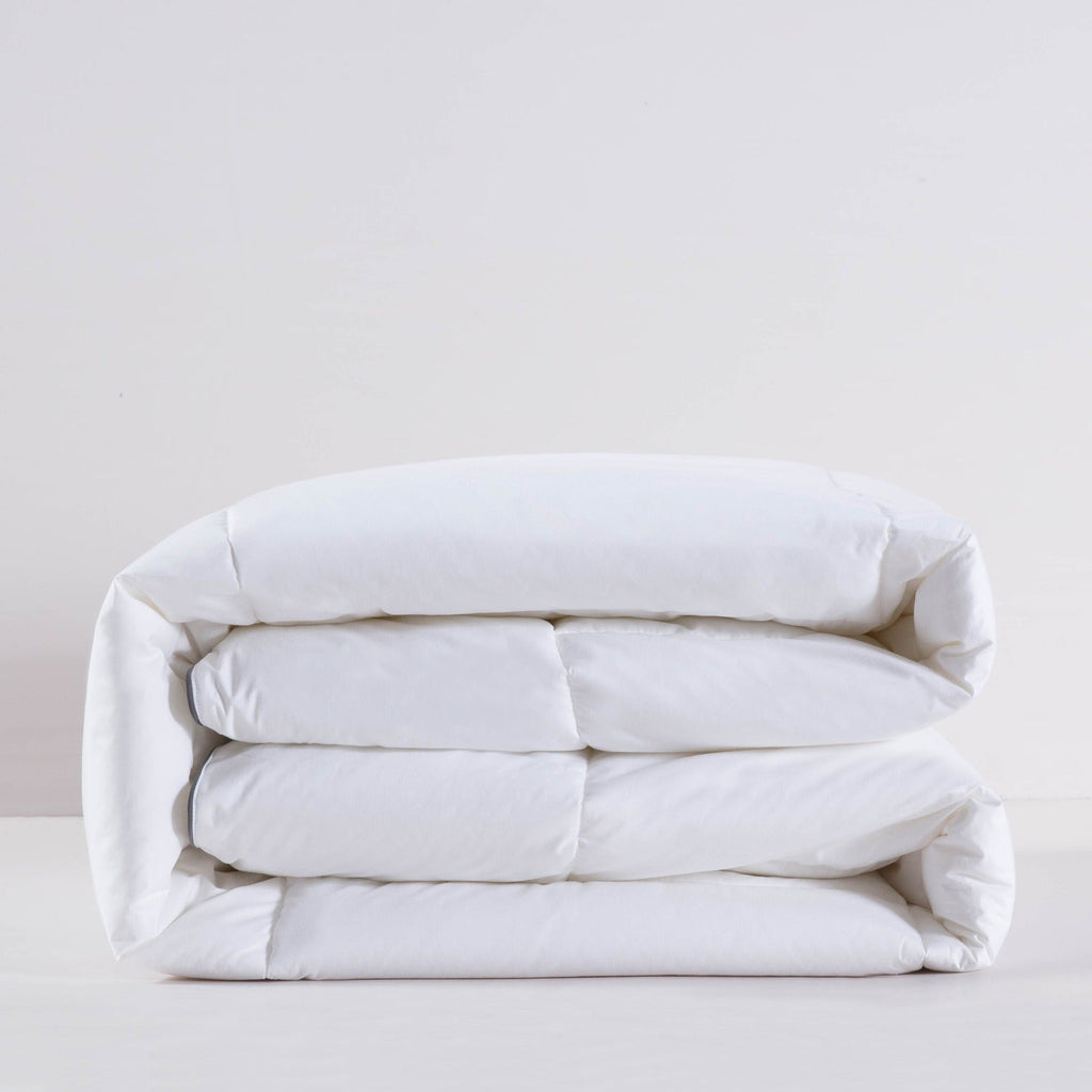 Folded white comforter on a light gray background