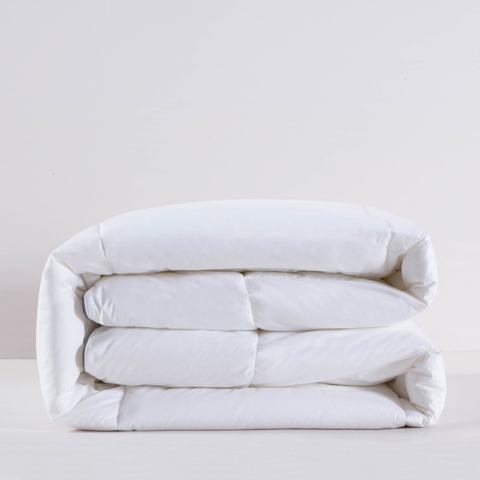 Folded white comforter on a light gray background