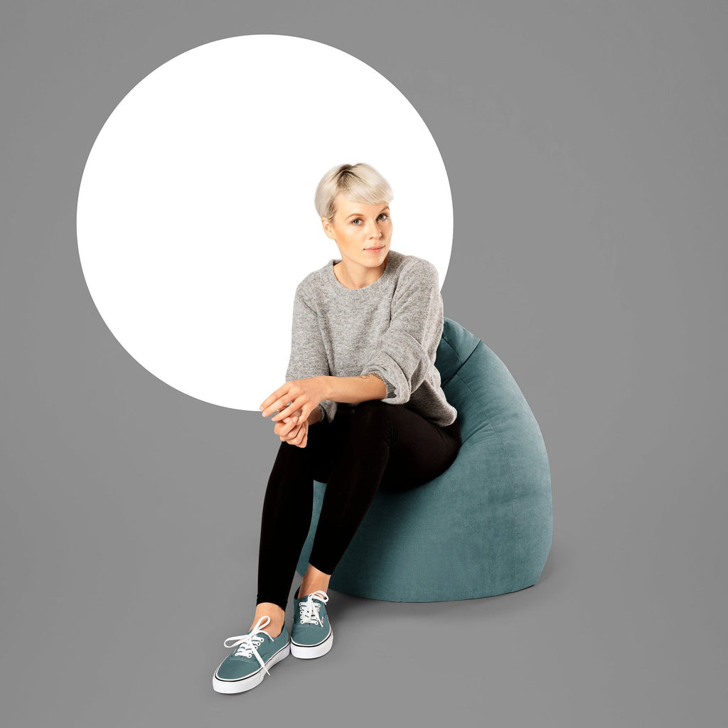 Woman sitting on a teal bean bag chair with a gray background