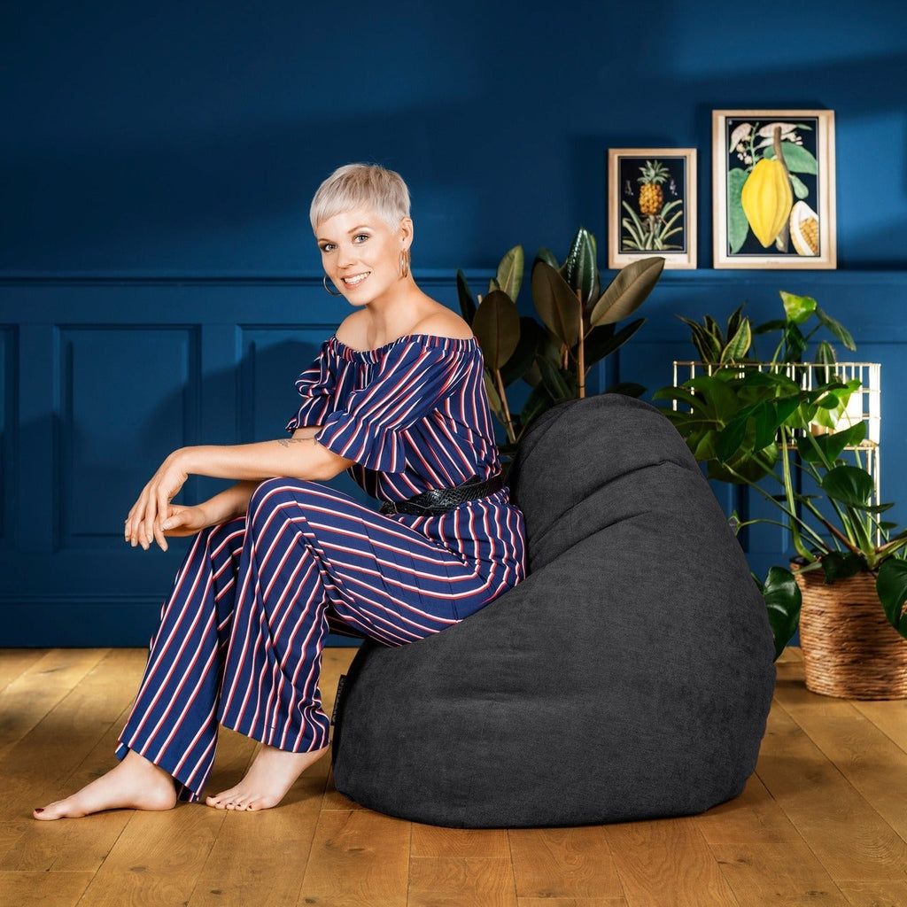 Woman sitting on a bean bag chair in a room with blue walls and framed pictures.