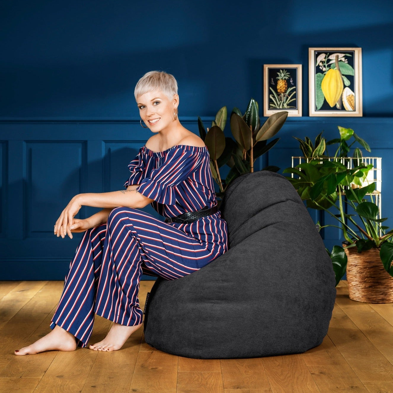 Woman sitting on a bean bag chair in a room with blue walls and framed pictures.