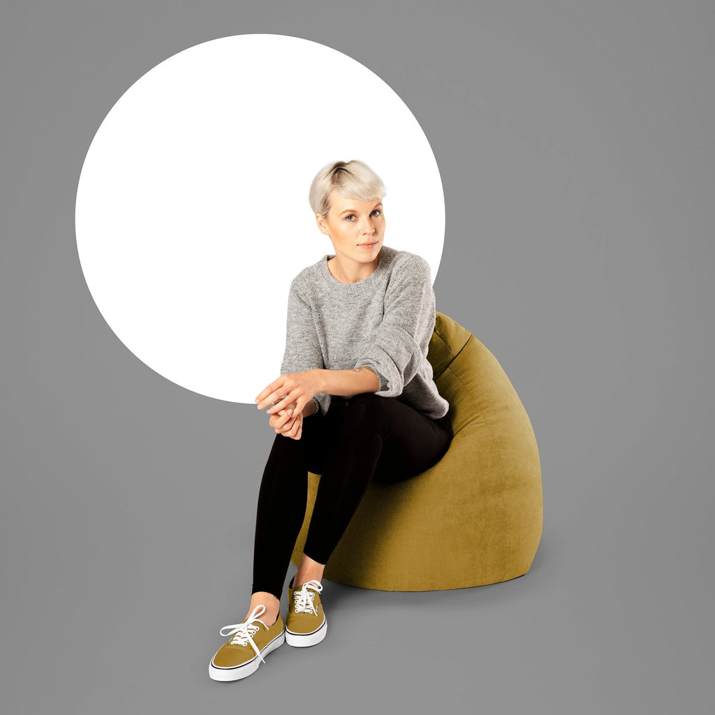 Woman sitting on a green bean bag chair with a gray background