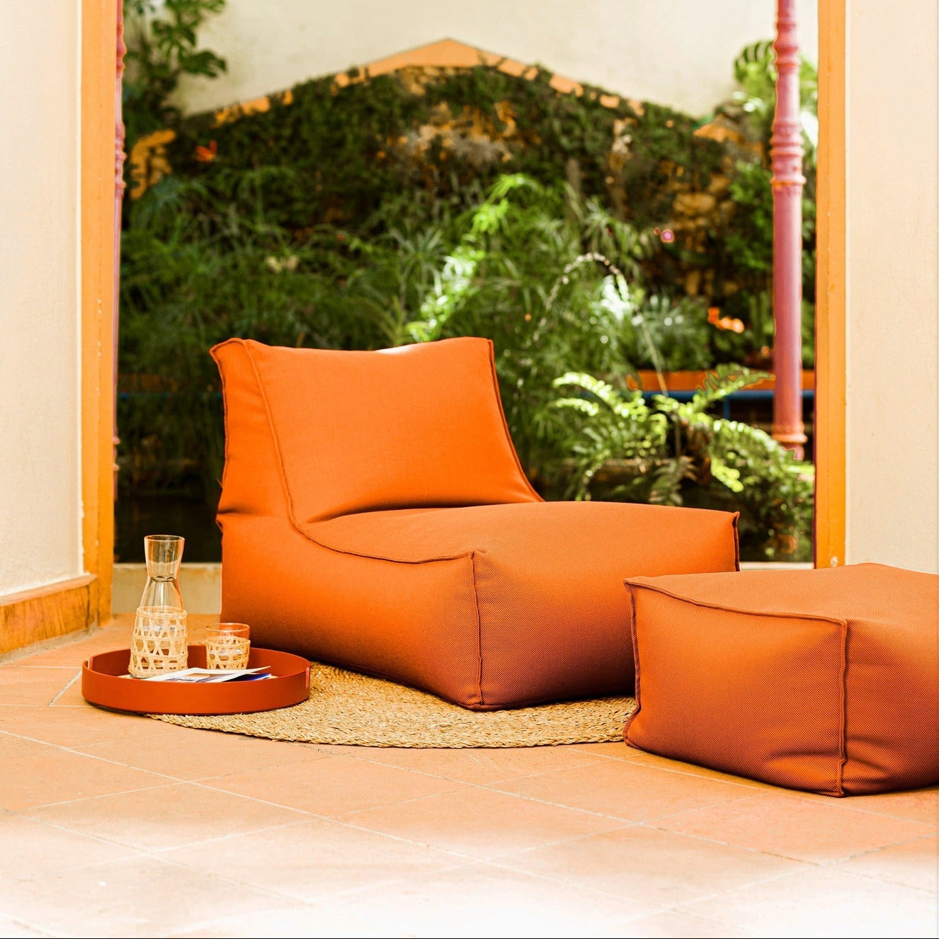Orange chair and ottoman in a room with a large window view of greenery