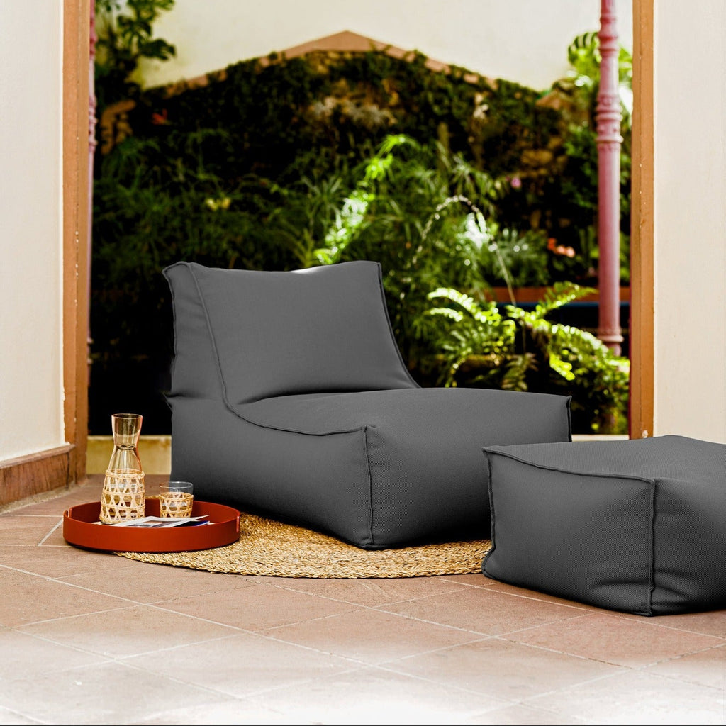 Gray bean bag chair and ottoman on a wooden floor with a scenic view outside.