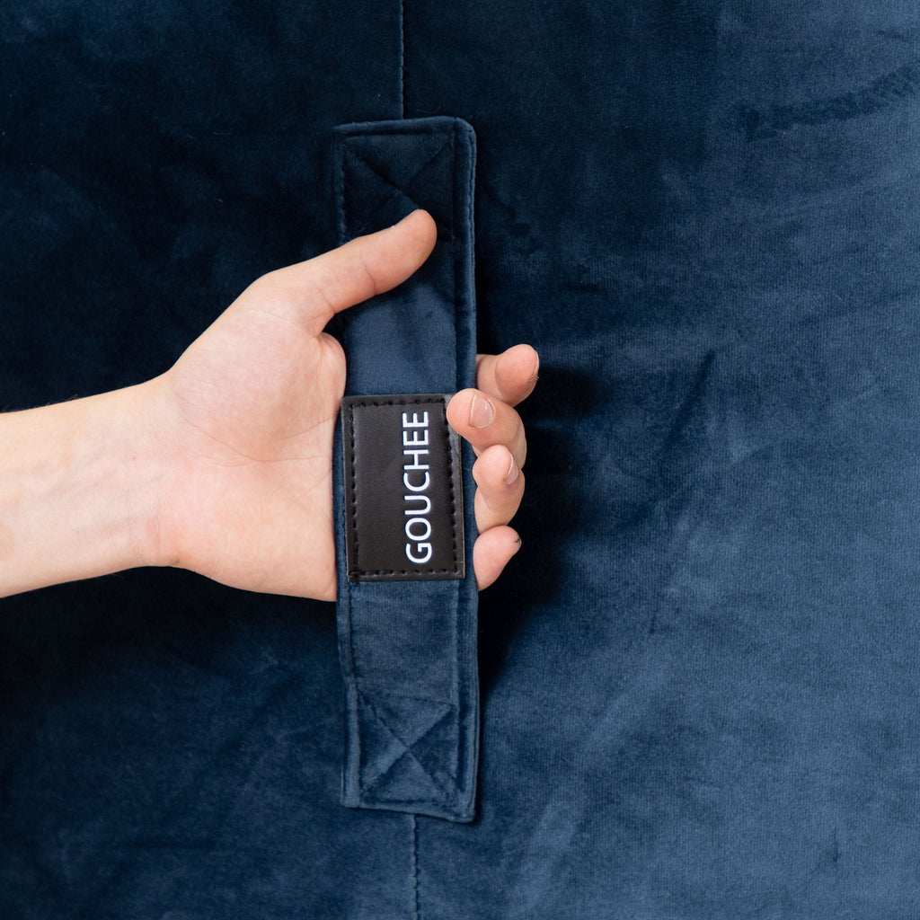 Hand holding a navy blue jacket with 'Gouchee' label