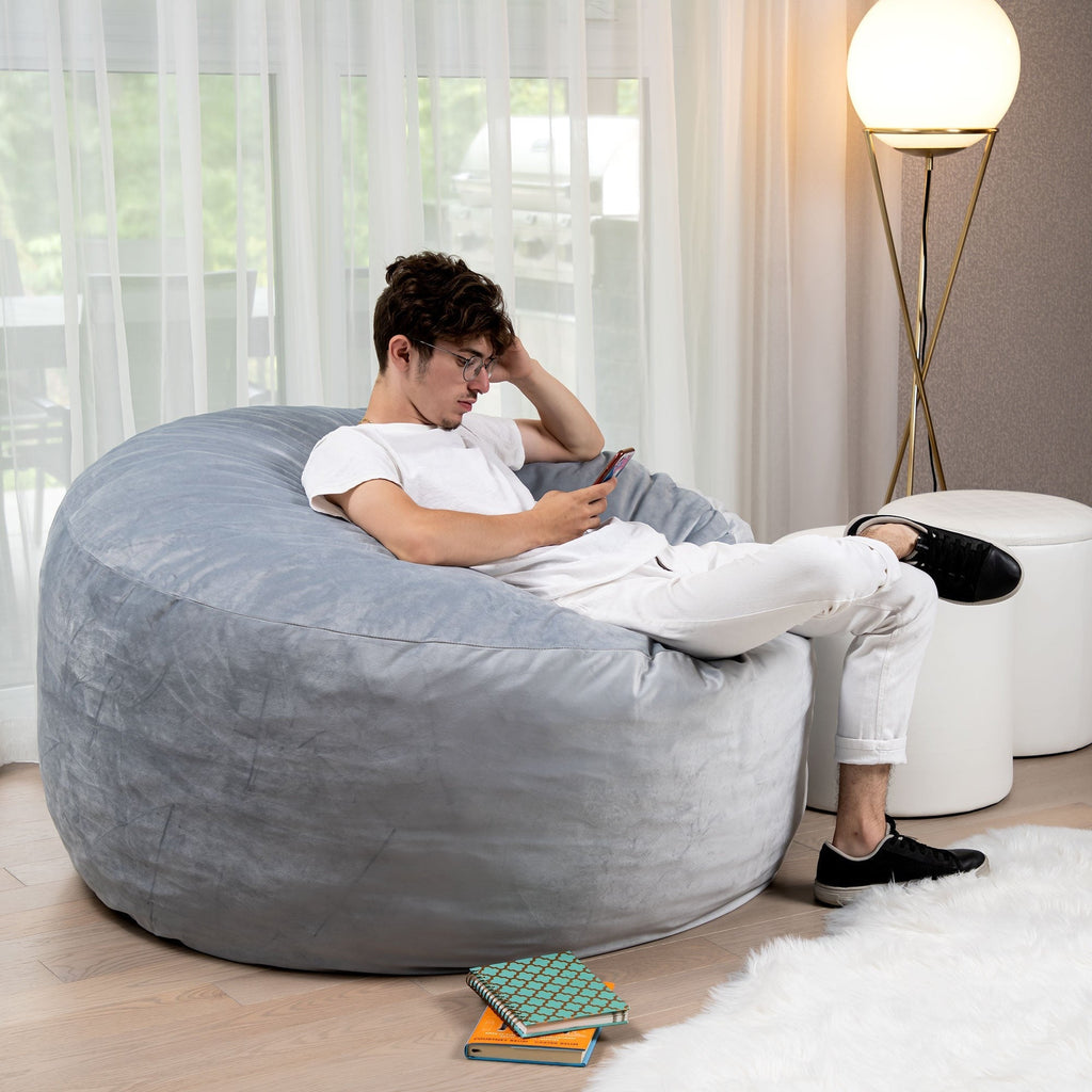Person sitting on a large gray bean bag chair in a modern living room.