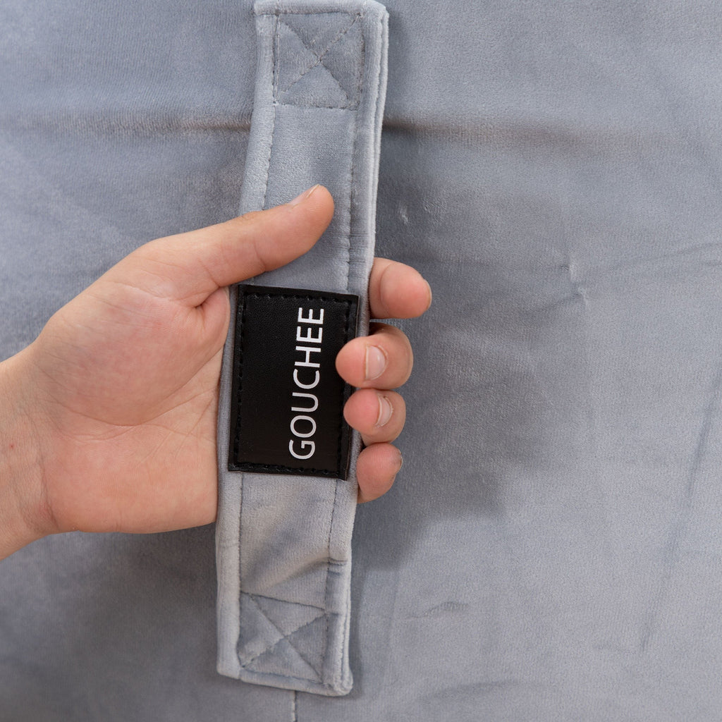 Hand holding a gray jacket with 'Gouchee' label against a matching gray background