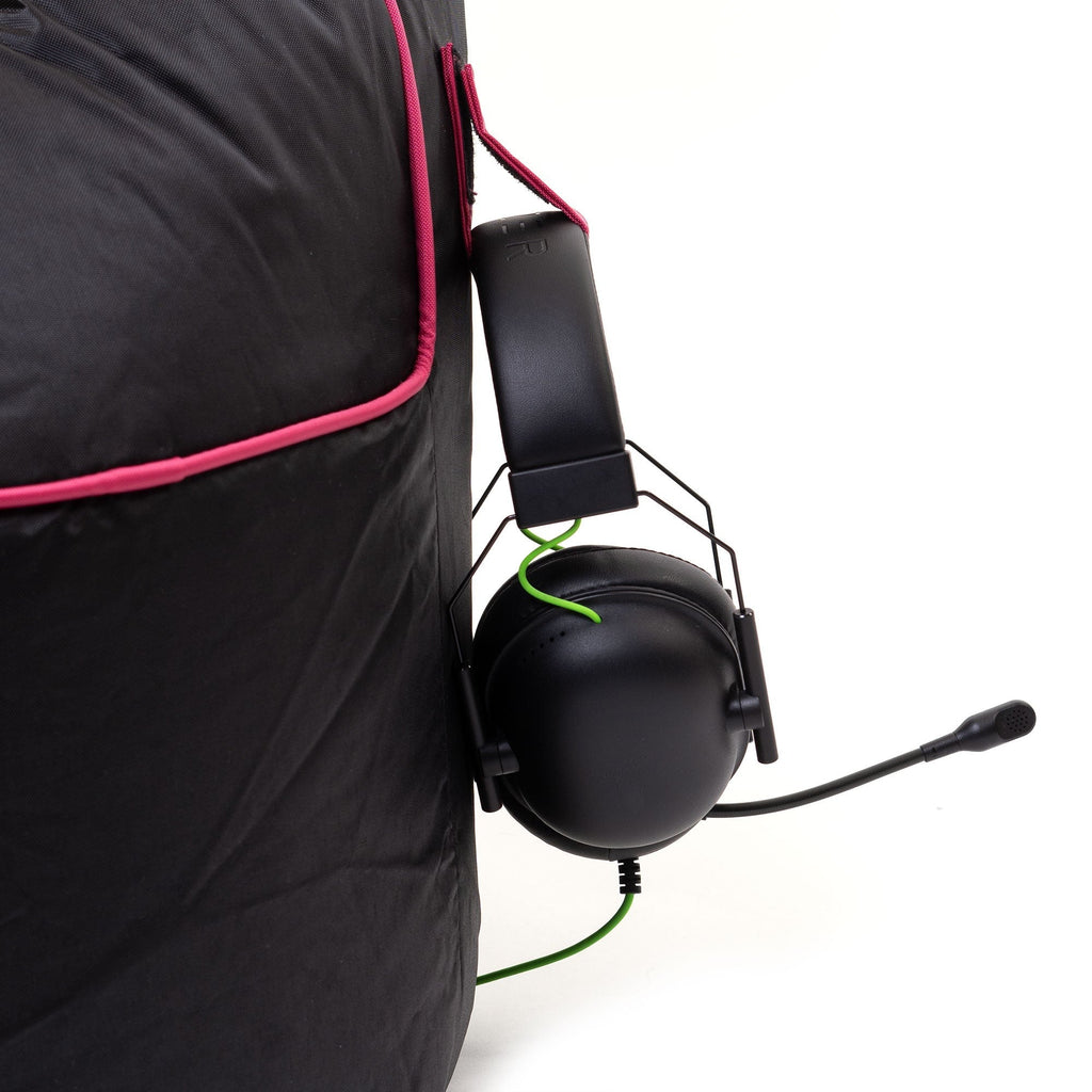 Black gaming headset with pink trim attached to a black bag on a white background