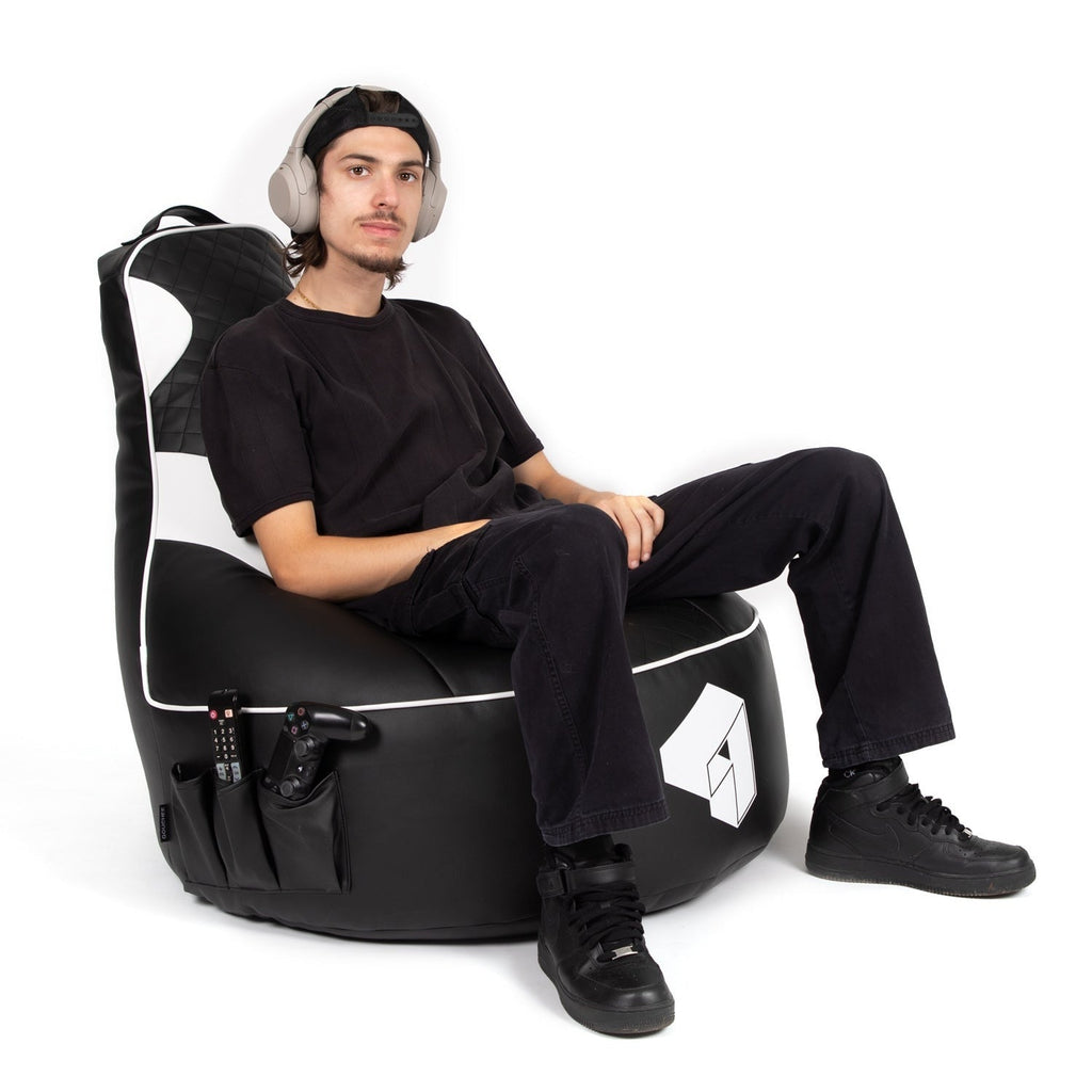 Person sitting on a black and white gaming chair with headphones on a white background