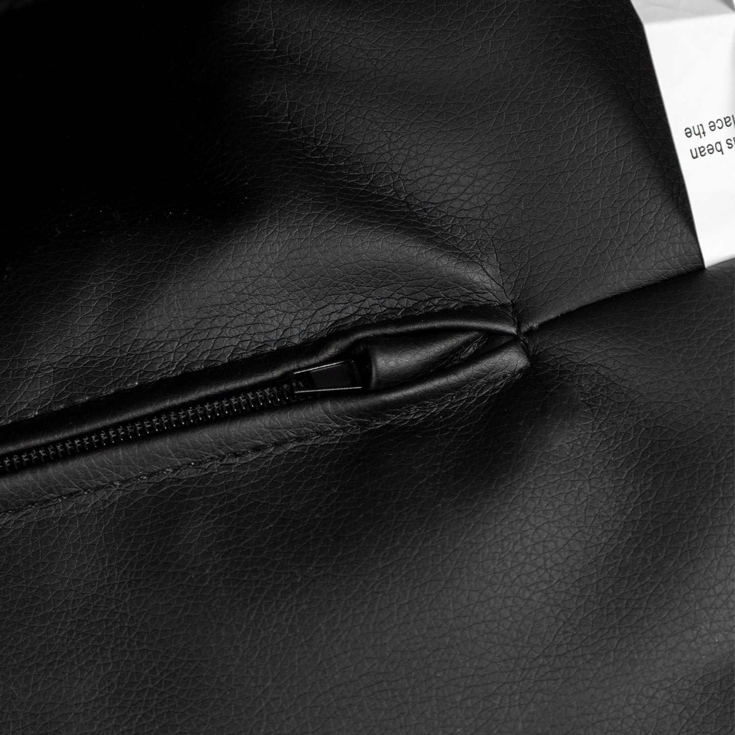 Close-up of a black leather bag with a zipper, showing texture and brand label.