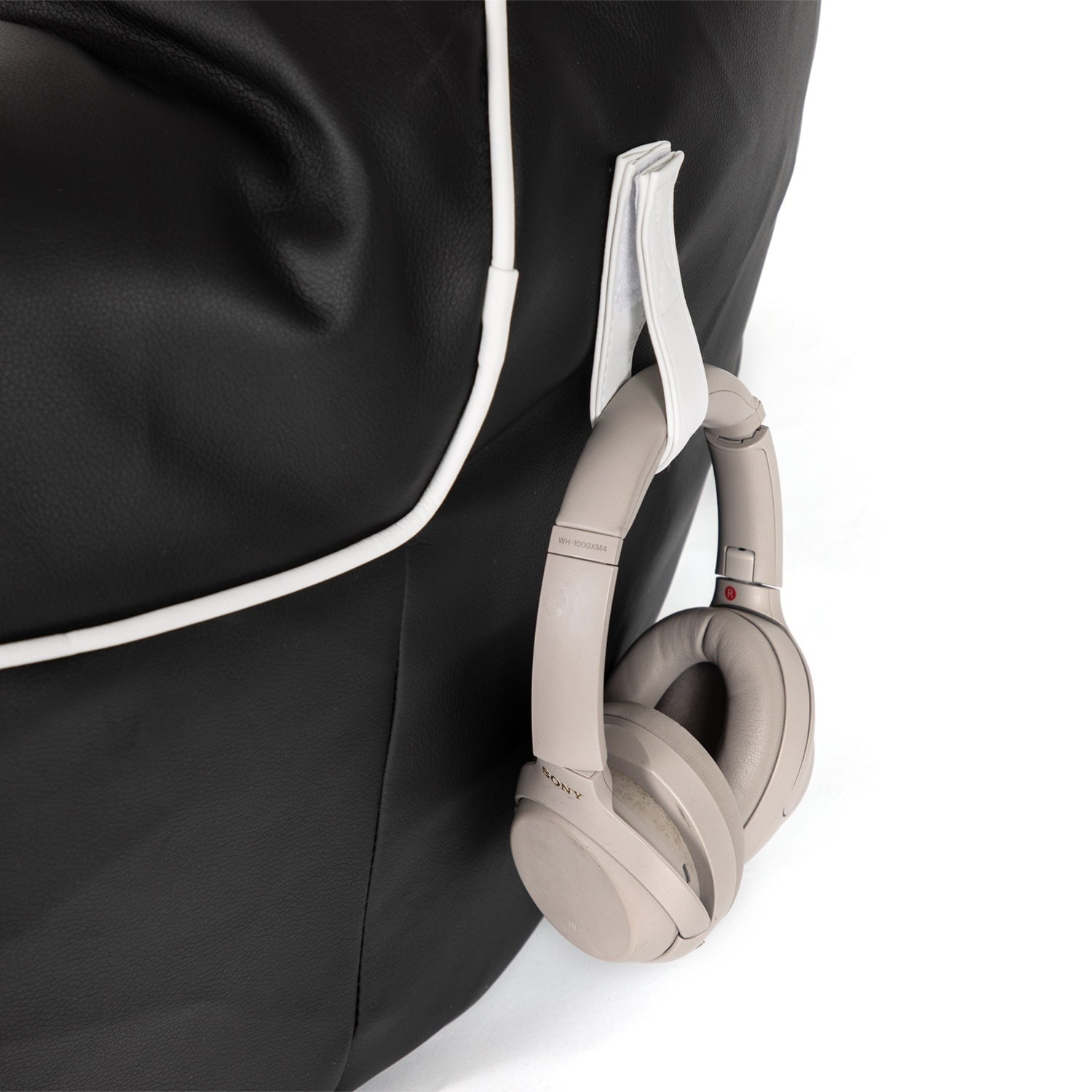 Beige headphones hanging on a black bag with white trim