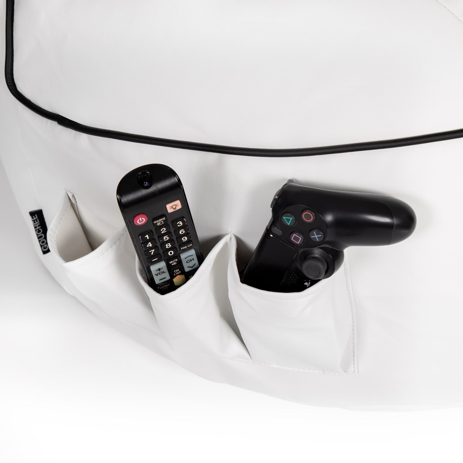 Black remote control and gaming controller in a white pocket with a white background
