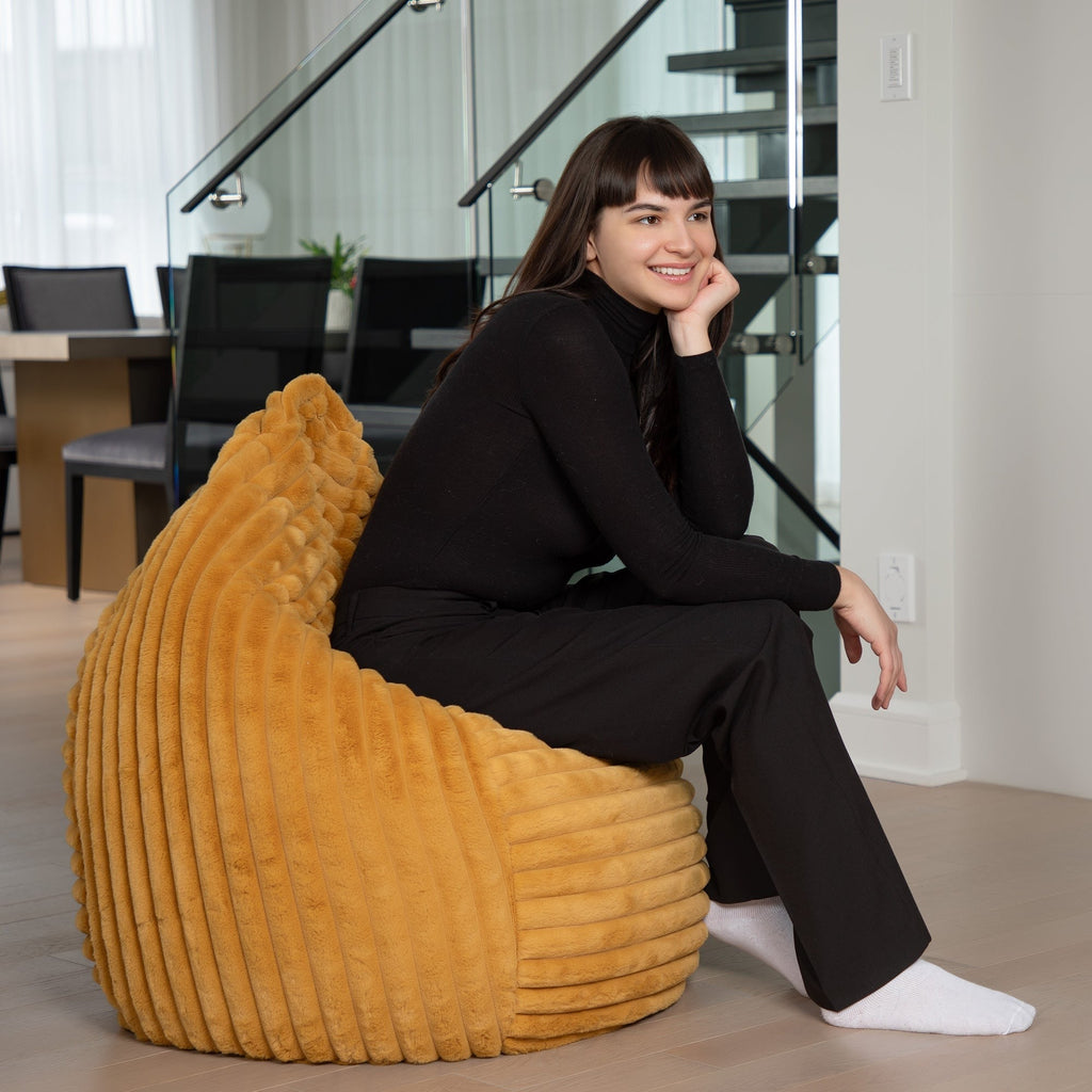 Woman sitting on a yellow bean bag chair in a modern indoor setting