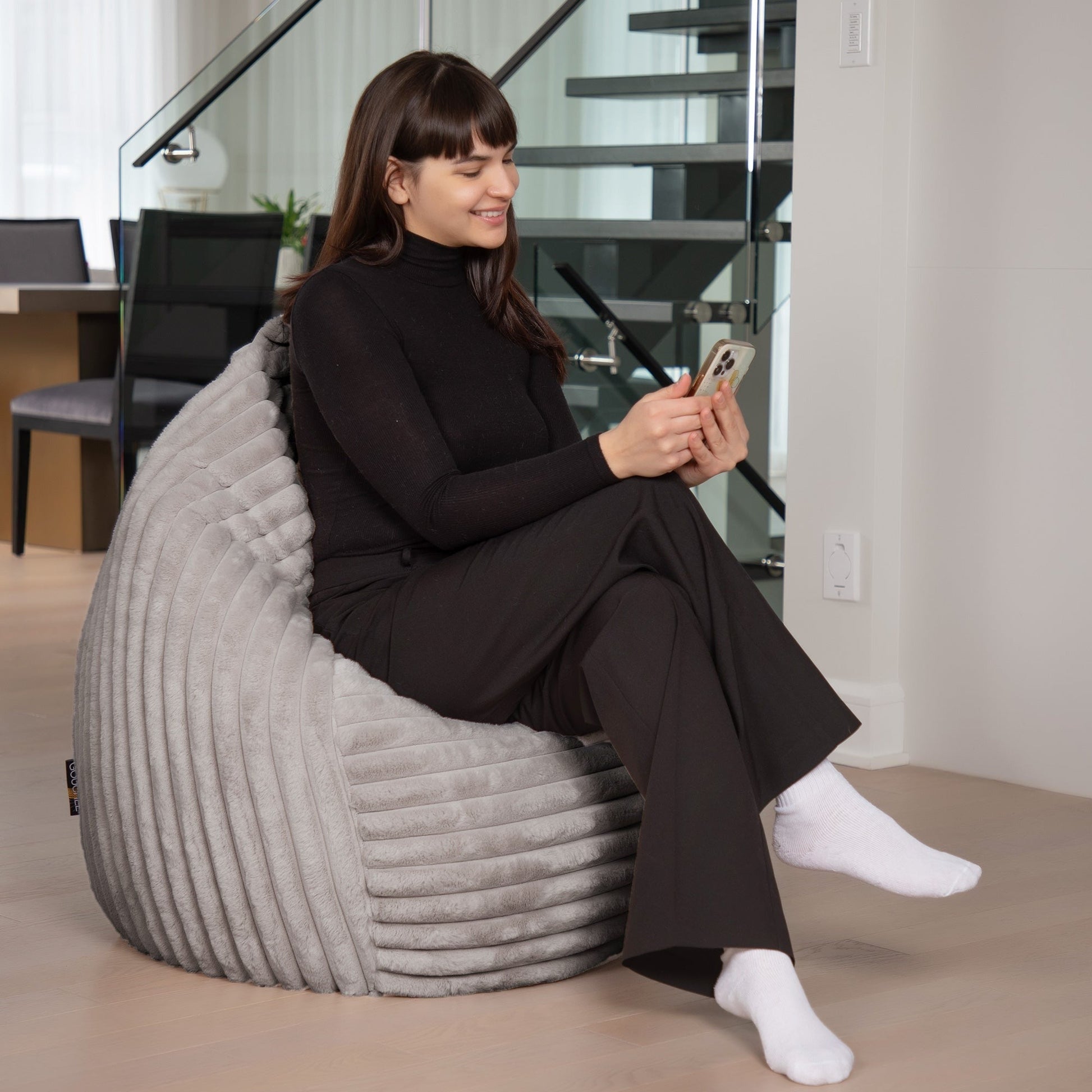 Woman sitting on a textured gray chair in a modern indoor setting.