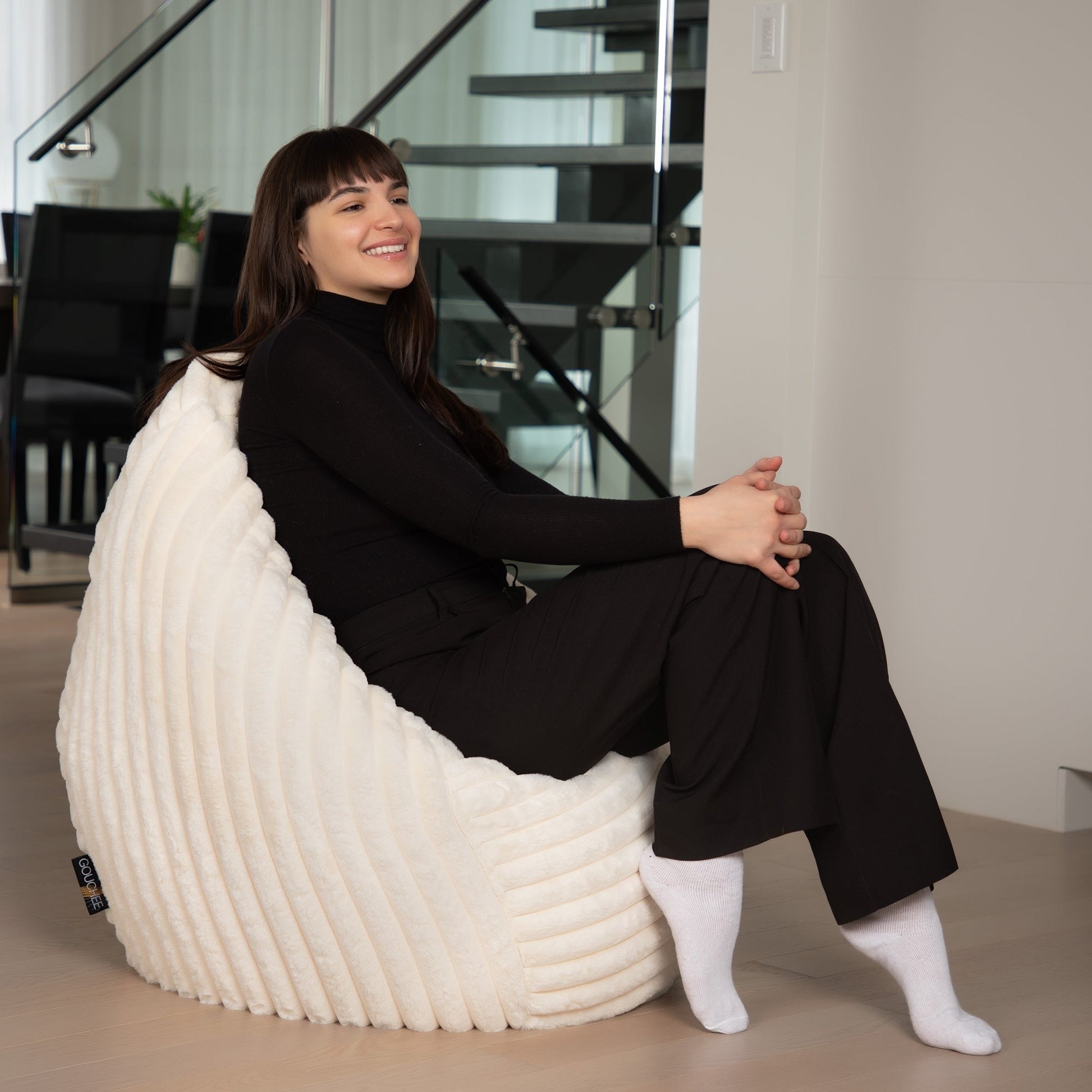 Woman sitting on a white bean bag chair in a modern indoor setting