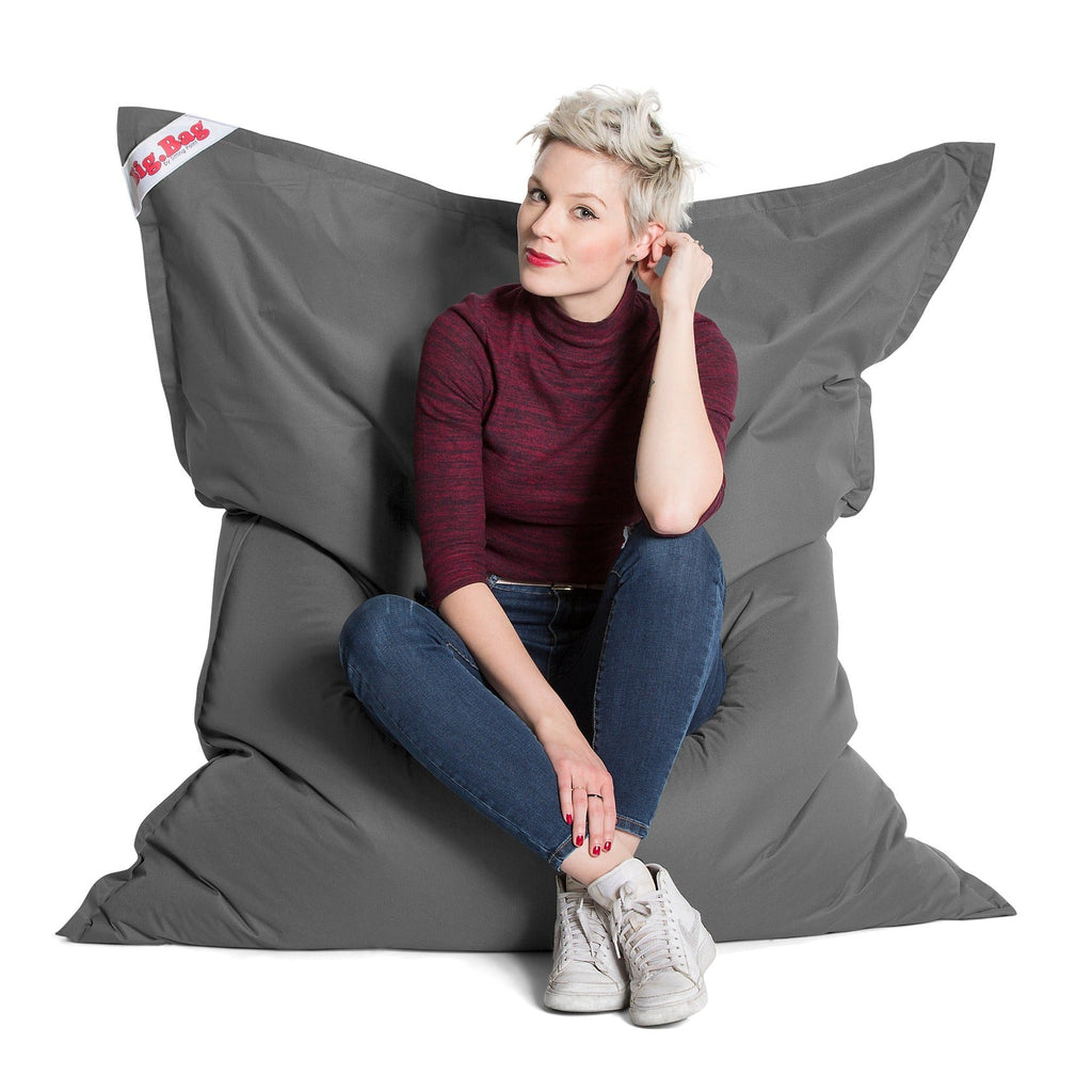 Person sitting on a large gray bean bag chair with a white background
