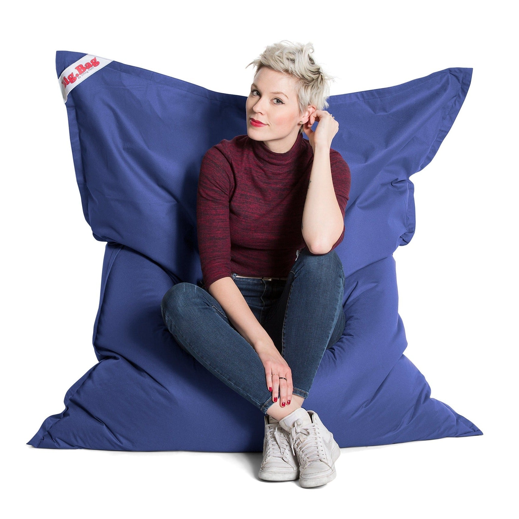 Person sitting on a large blue bean bag chair against a white background