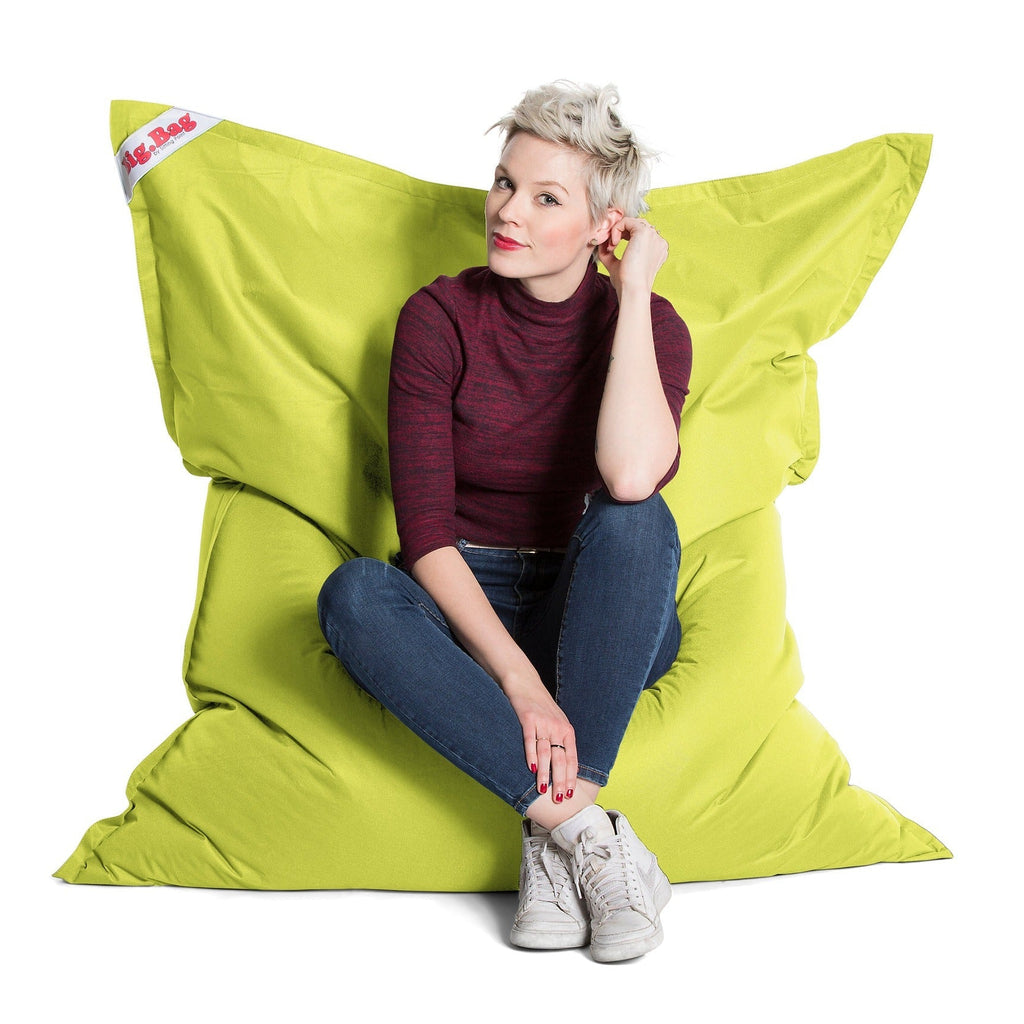 Woman sitting on a large green bean bag chair with a white background