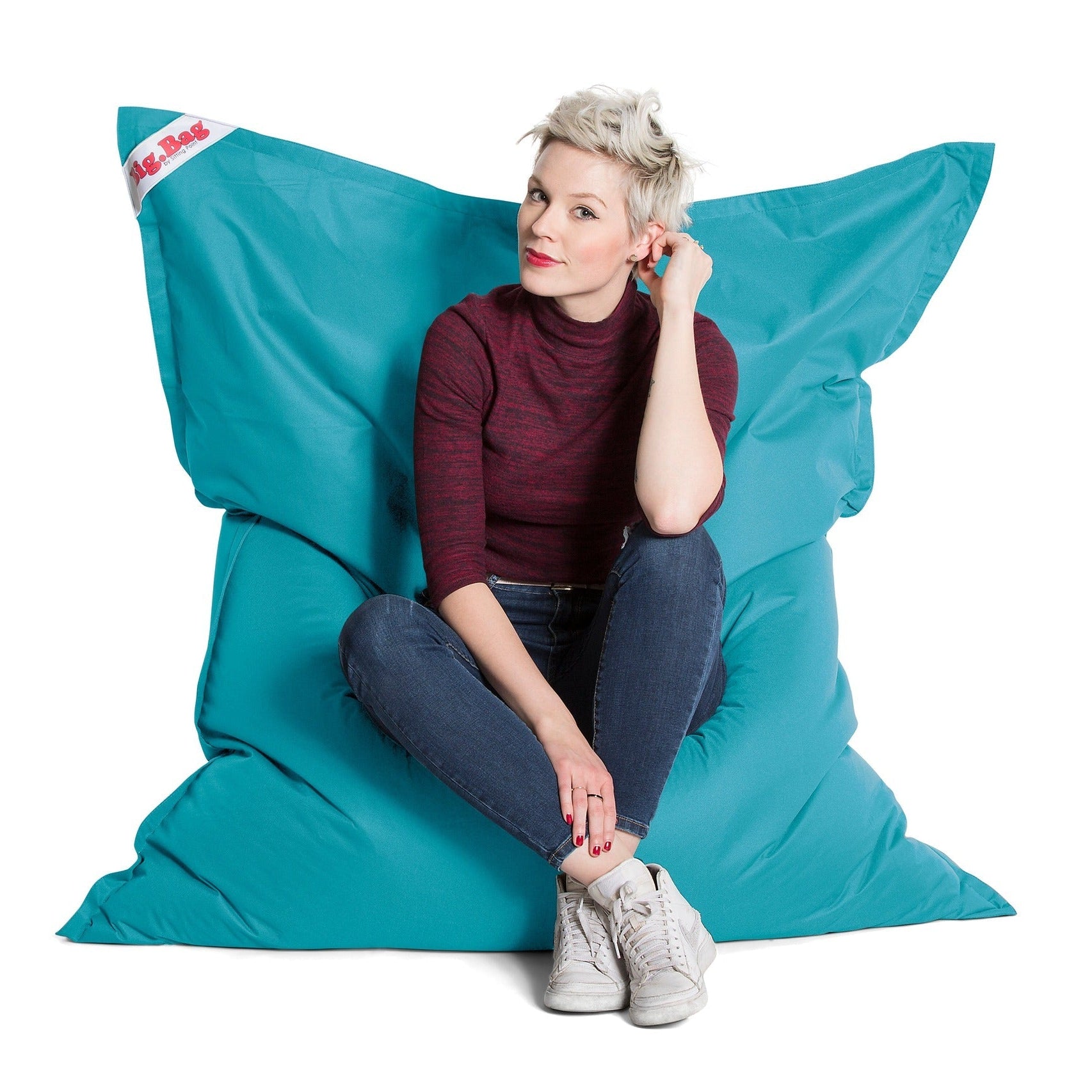 Person sitting on a large blue bean bag chair with a white background
