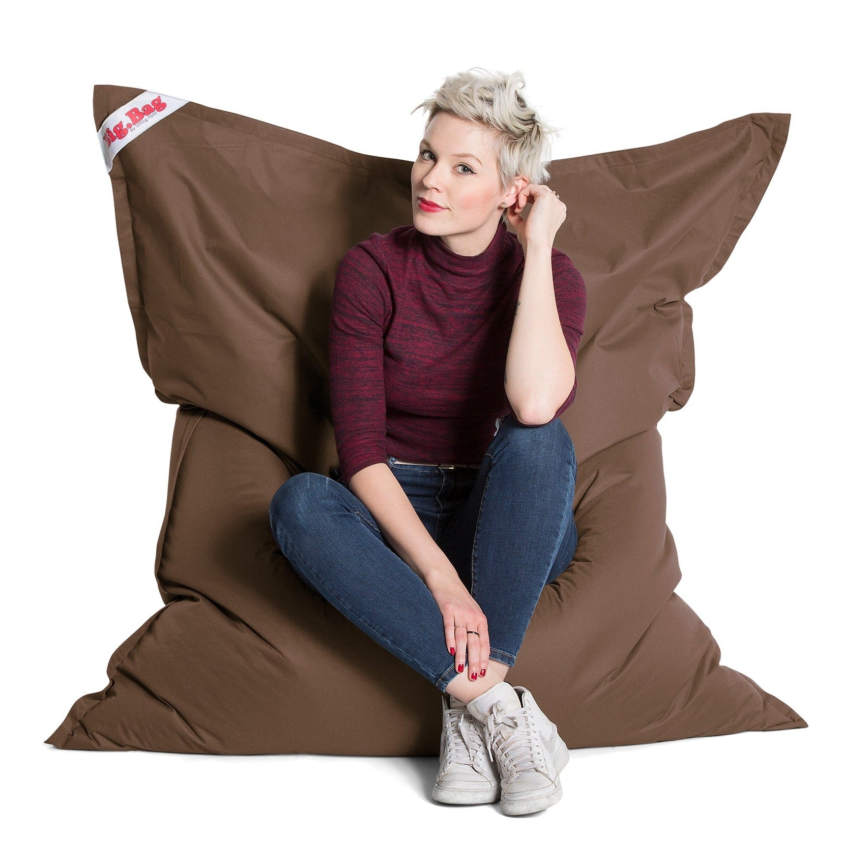 Woman sitting on a large brown bean bag chair with a white background