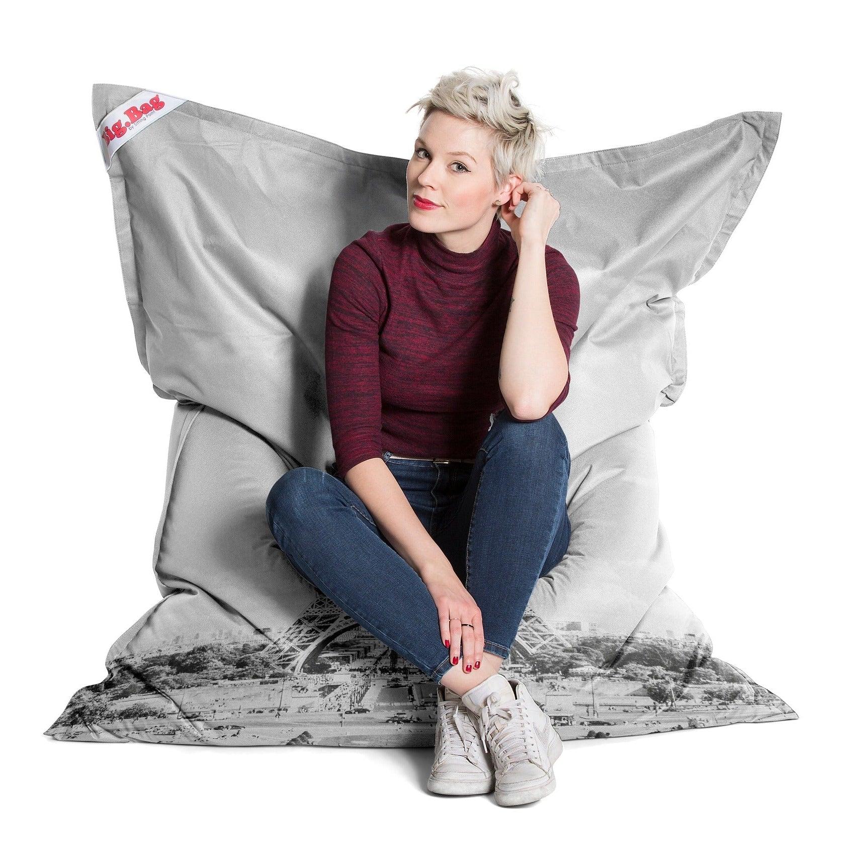 Person sitting on a large gray bean bag chair with a white background