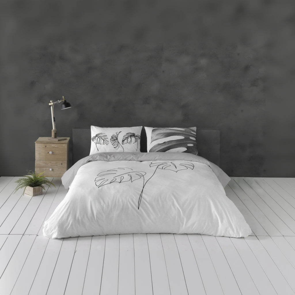 Bed with floral-patterned bedding in a minimalistic bedroom setting.