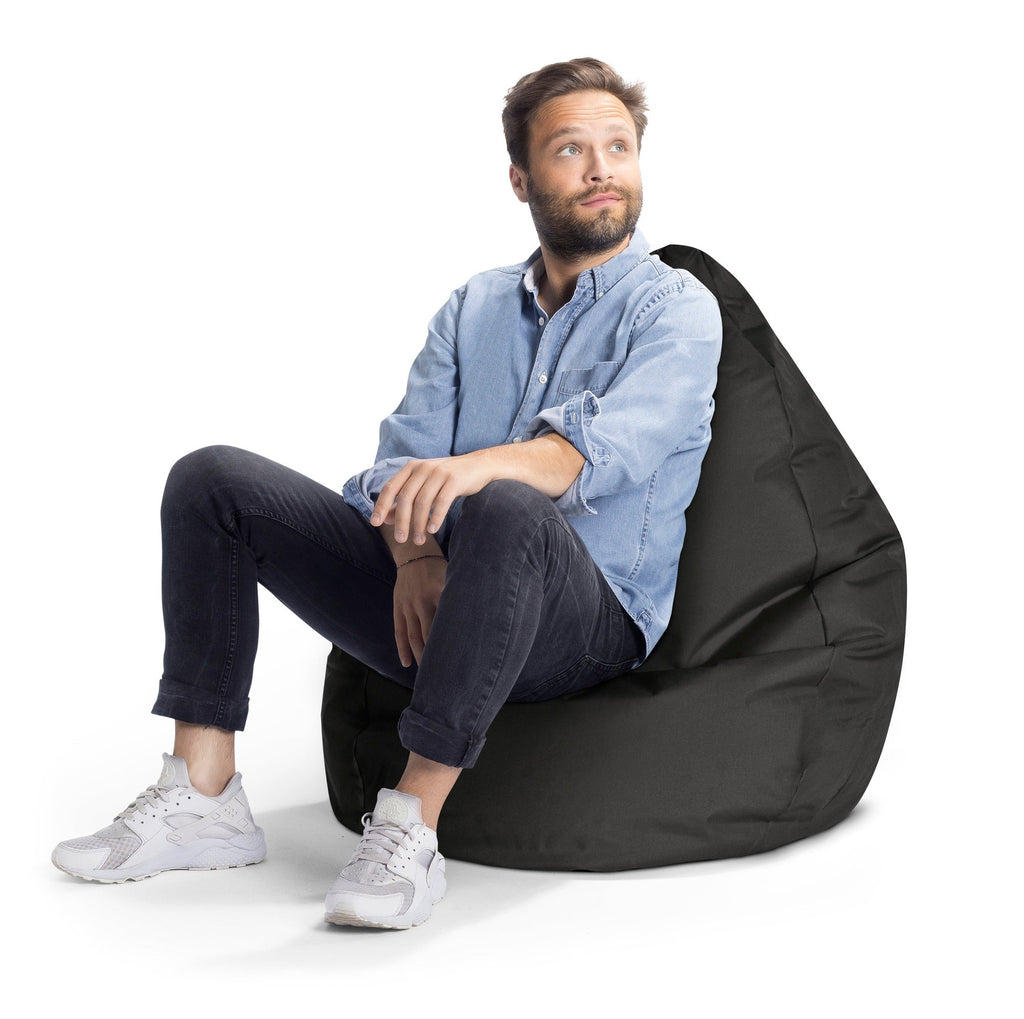 Man sitting on a black bean bag chair against a white background
