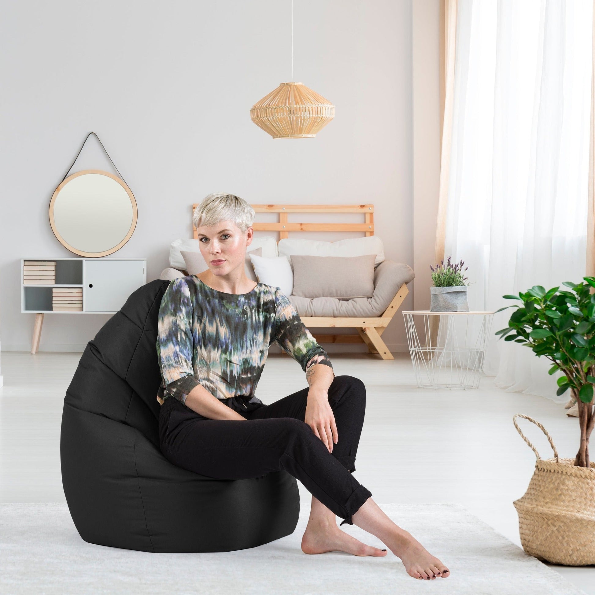 Woman sitting on a black bean bag chair in a modern living room.