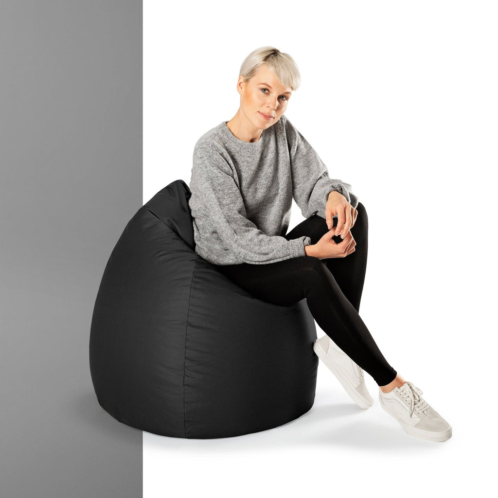 Woman sitting on a black bean bag chair against a gray background