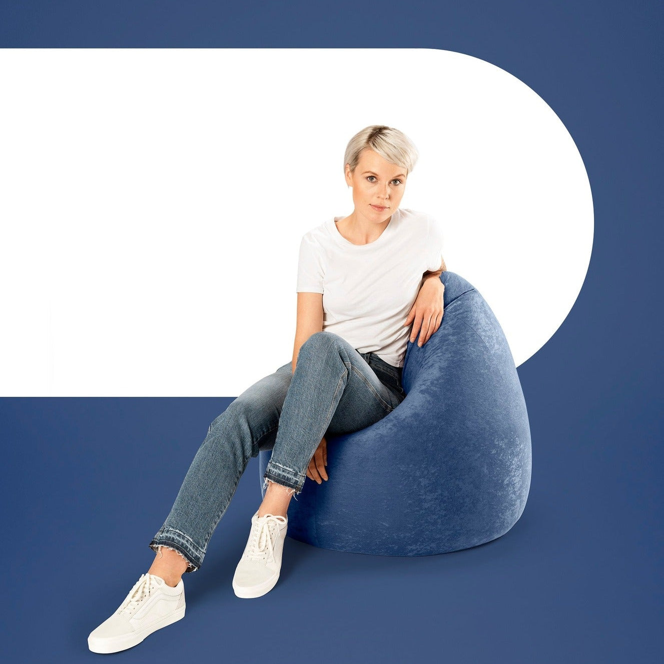 Woman sitting on a blue bean bag chair against a blue background