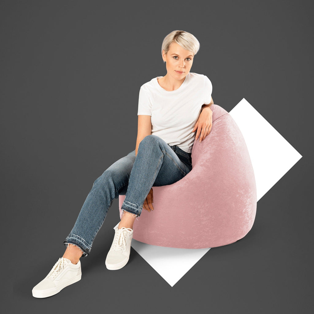 Woman sitting on a pink bean bag chair against a dark background