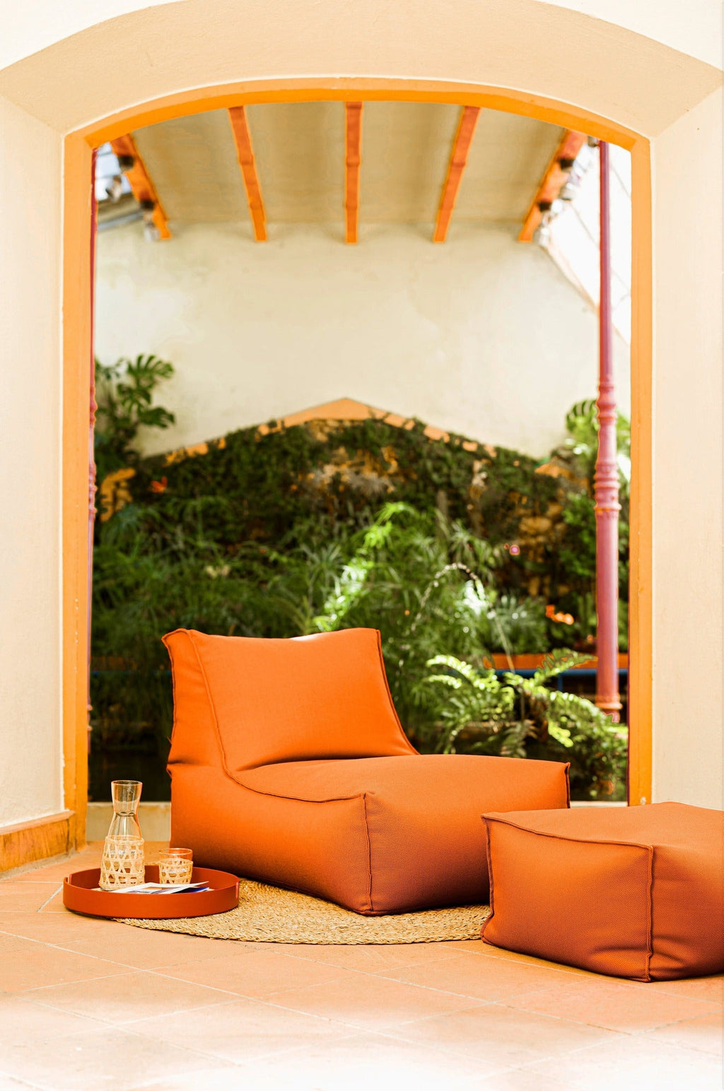 Orange chair and ottoman in a room with a large window view of greenery