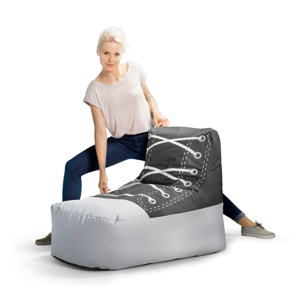 Person sitting on a large gray and black shoe-shaped bean bag chair.