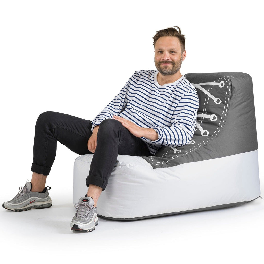 Man sitting on a modern, gray and white chair against a white background