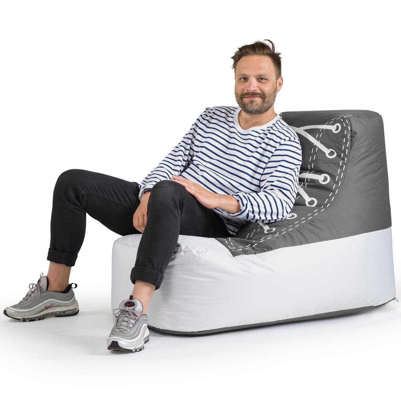 Man sitting on a modern, gray and white chair against a white background
