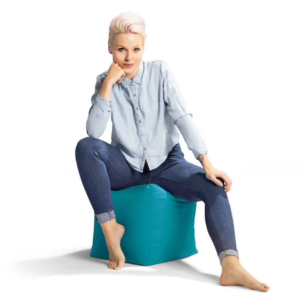 Woman sitting on a teal bean bag chair against a white background