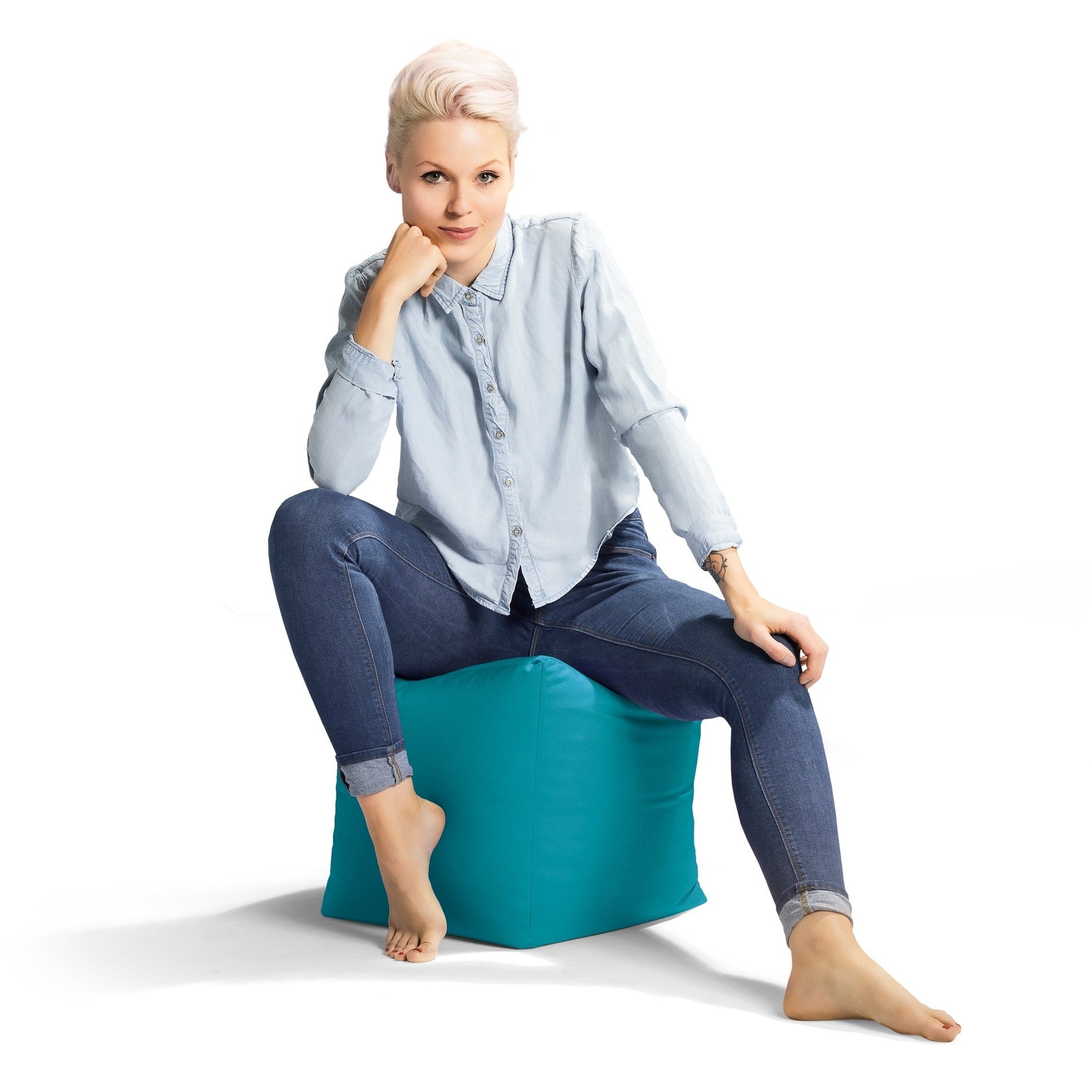 Woman sitting on a teal bean bag chair against a white background
