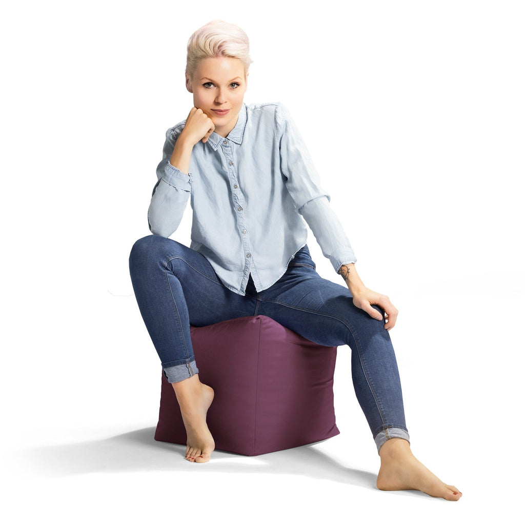Woman sitting on a purple bean bag chair against a white background