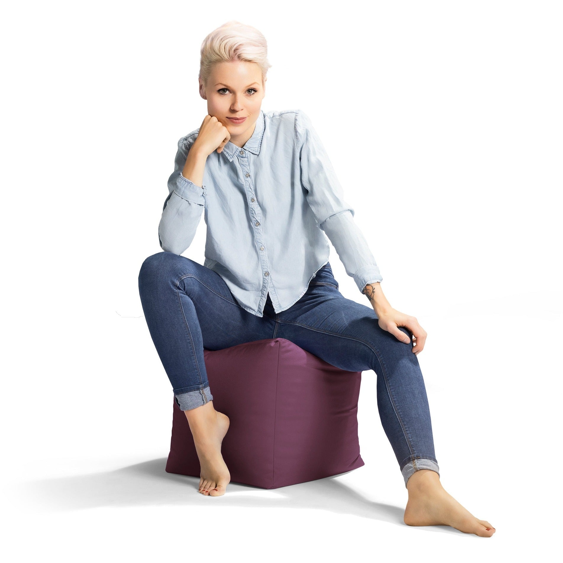 Woman sitting on a purple bean bag chair against a white background