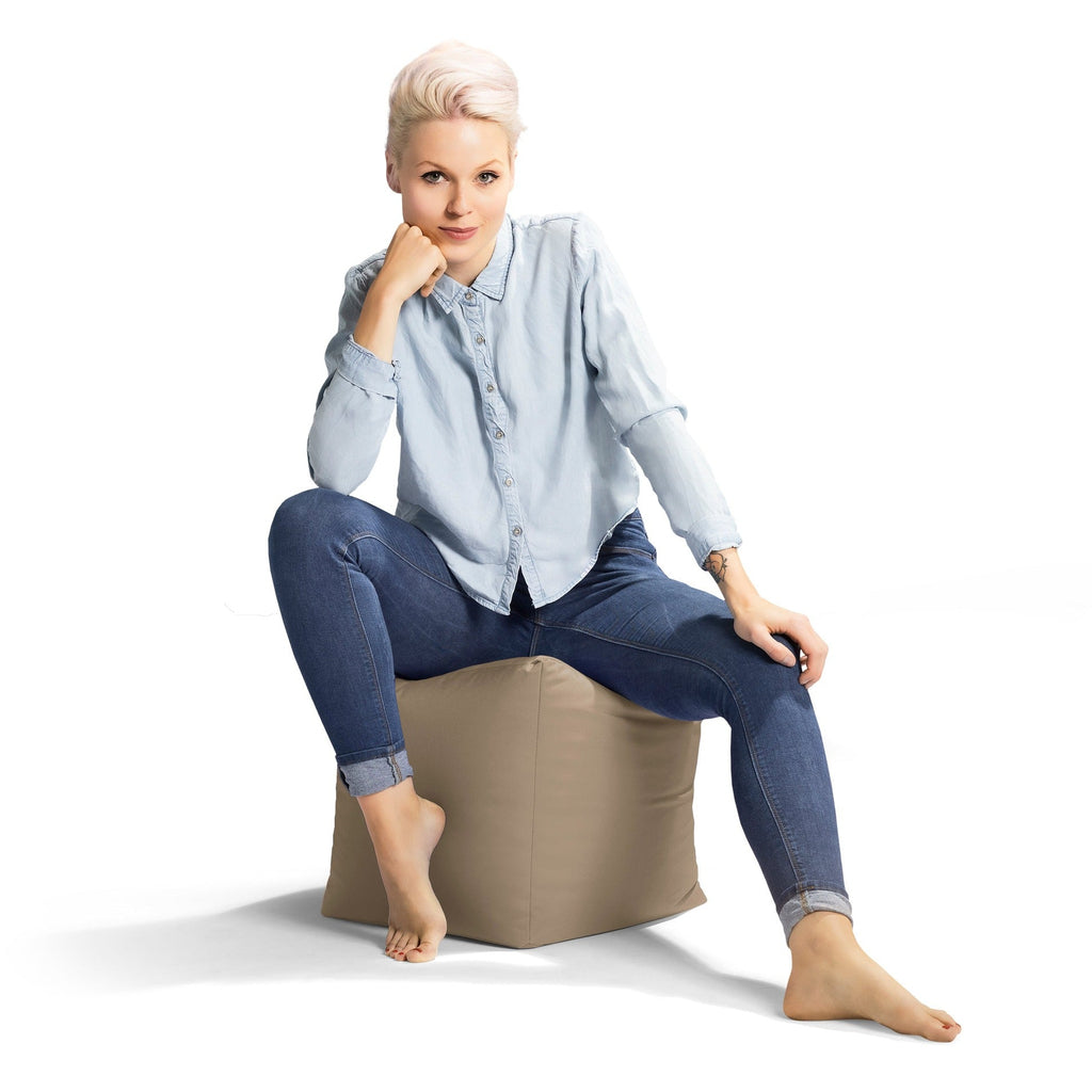 Woman sitting on a beige bean bag chair against a white background