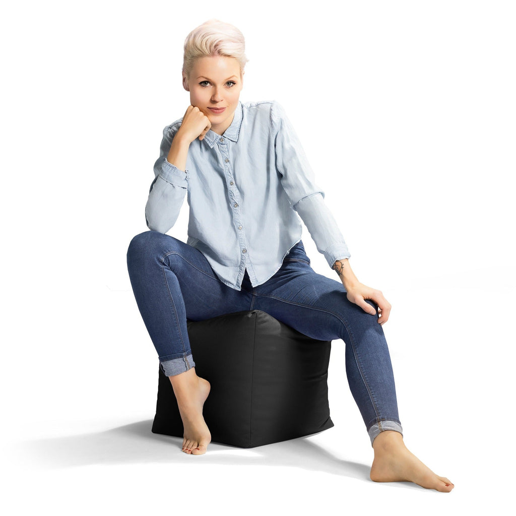 Woman sitting on a black bean bag chair against a white background