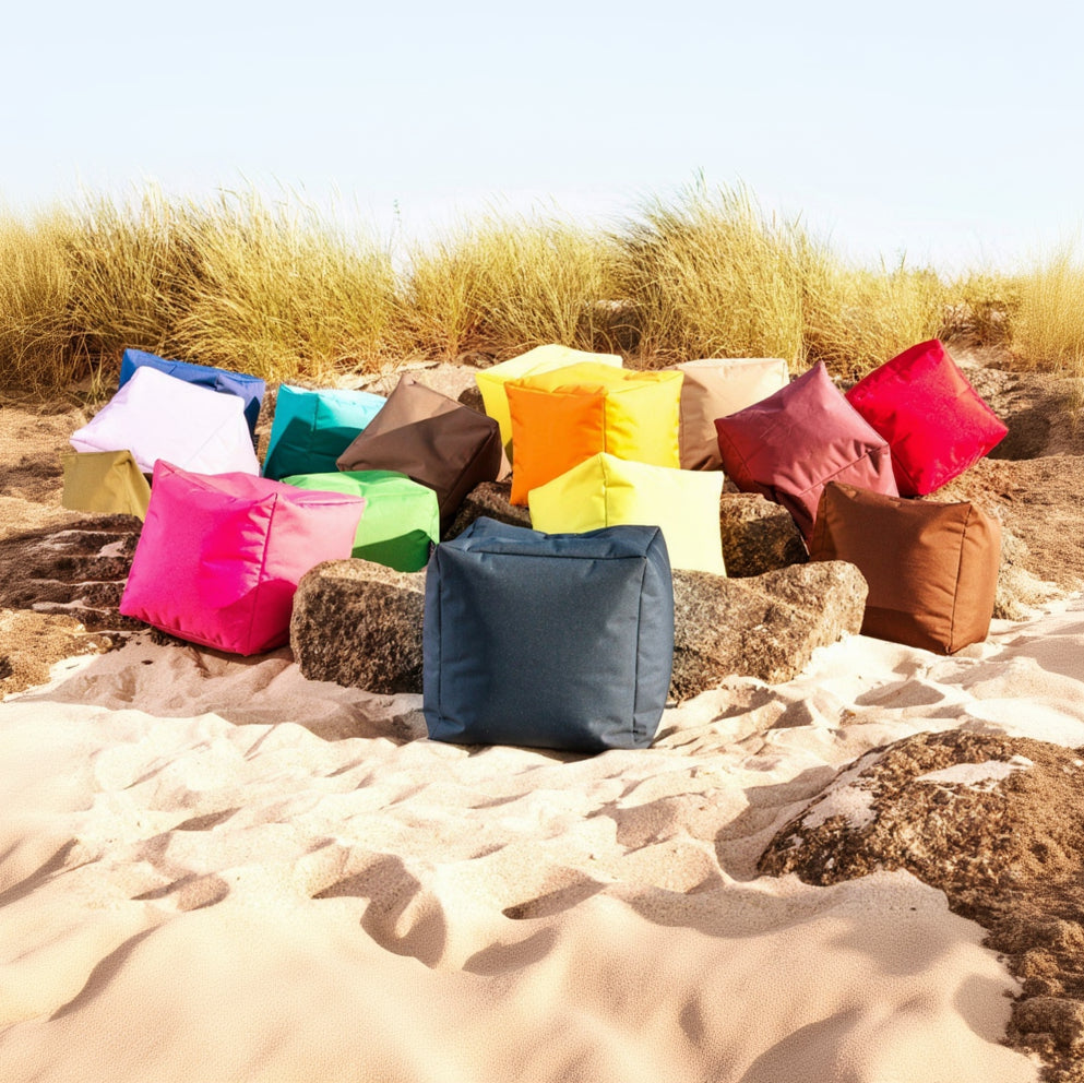 Colorful bean bags on a sandy beach with grass in the background