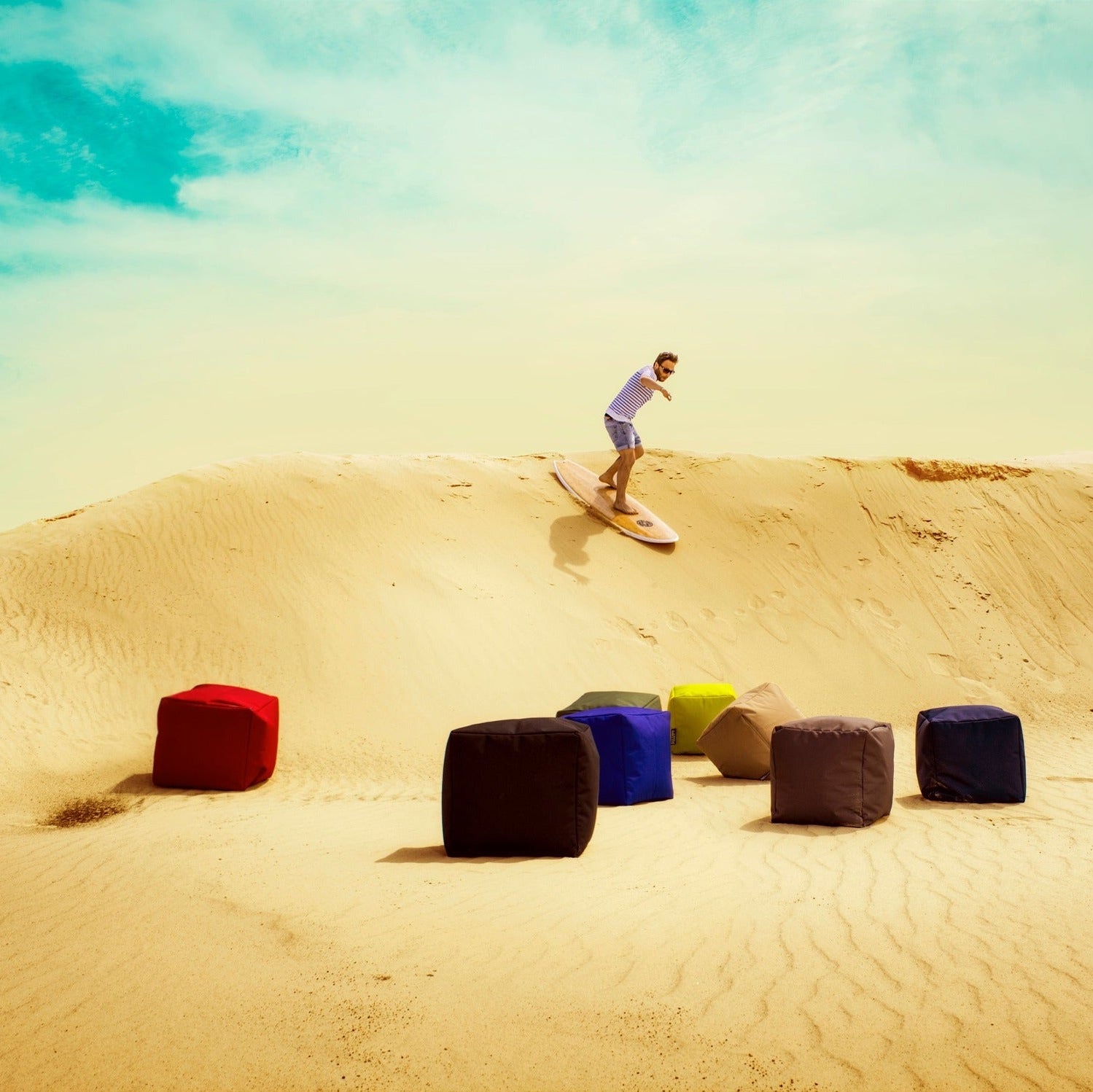 Person skateboarding on sand dunes with colorful cubes in the foreground