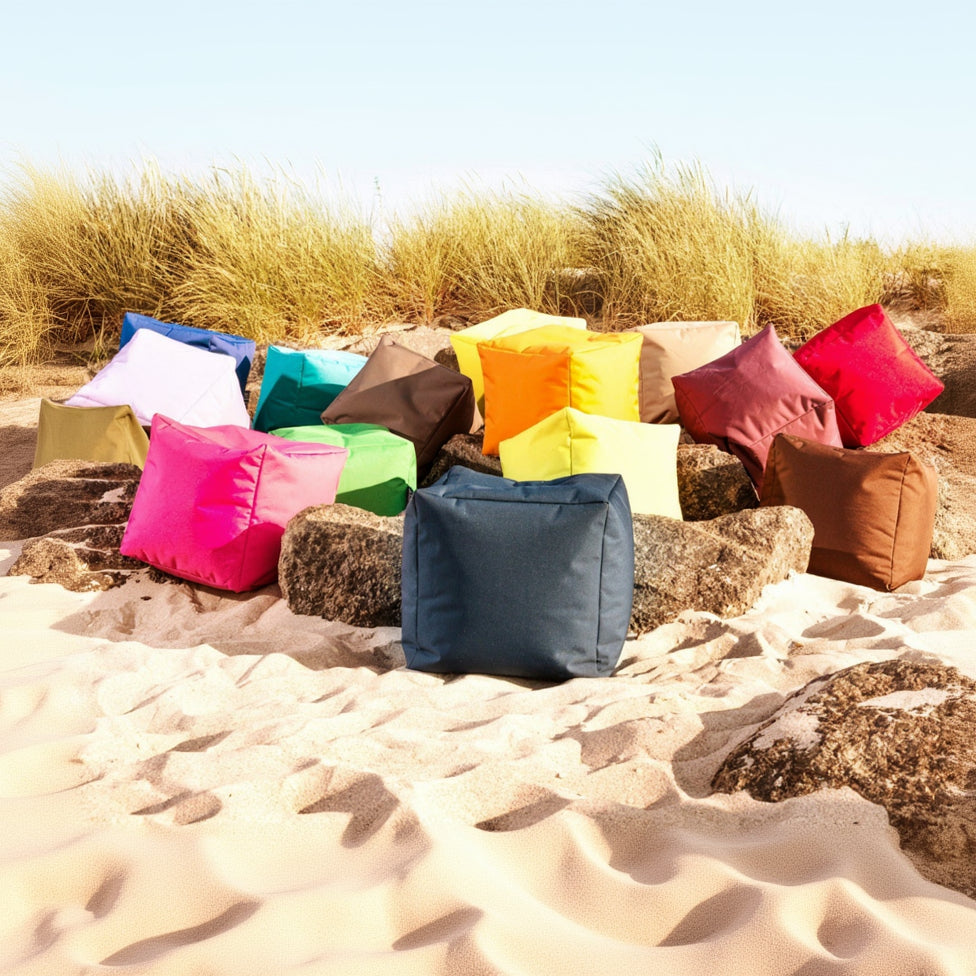Colorful bean bags on a sandy beach with grass in the background